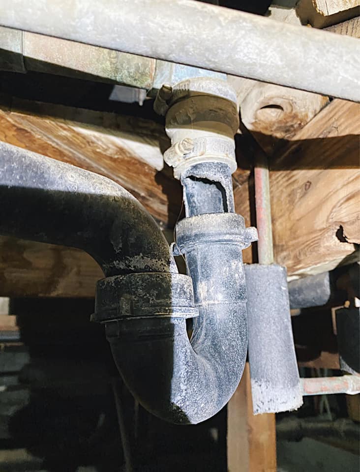 A plumber repairing pipes under a sink