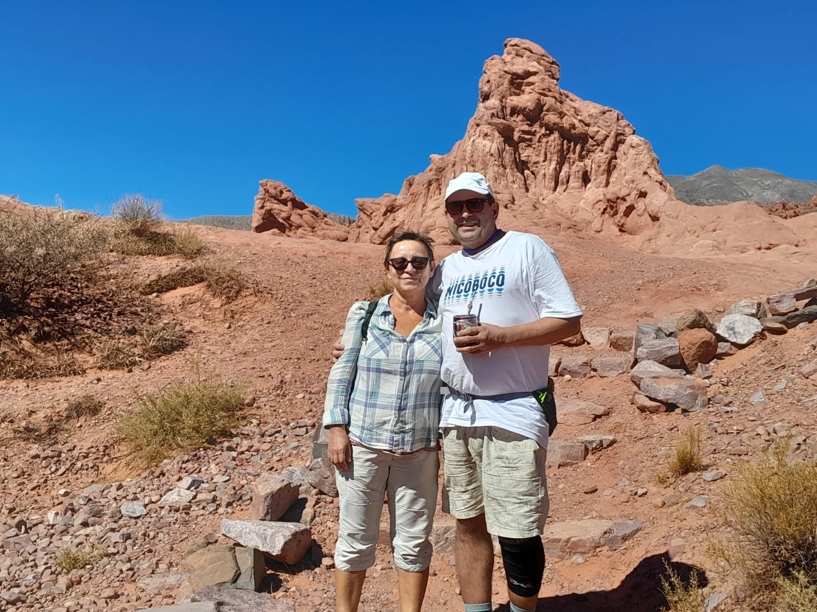 Mujer sentada sobre un tronco frente a una cascada doble en un bosque frondoso de Argentina.