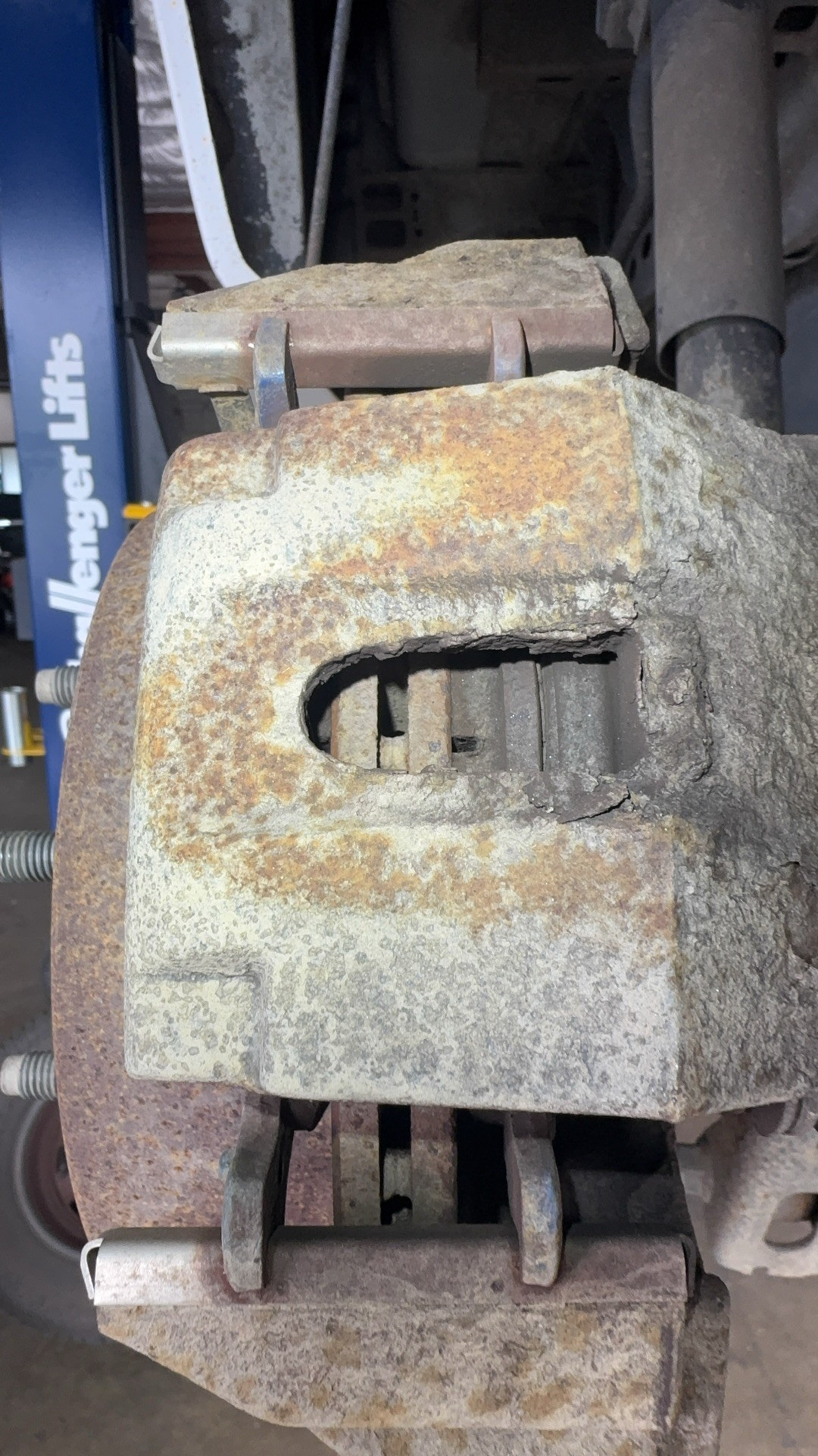 Caliper inspection window showing the brake pad separating from its backing plate