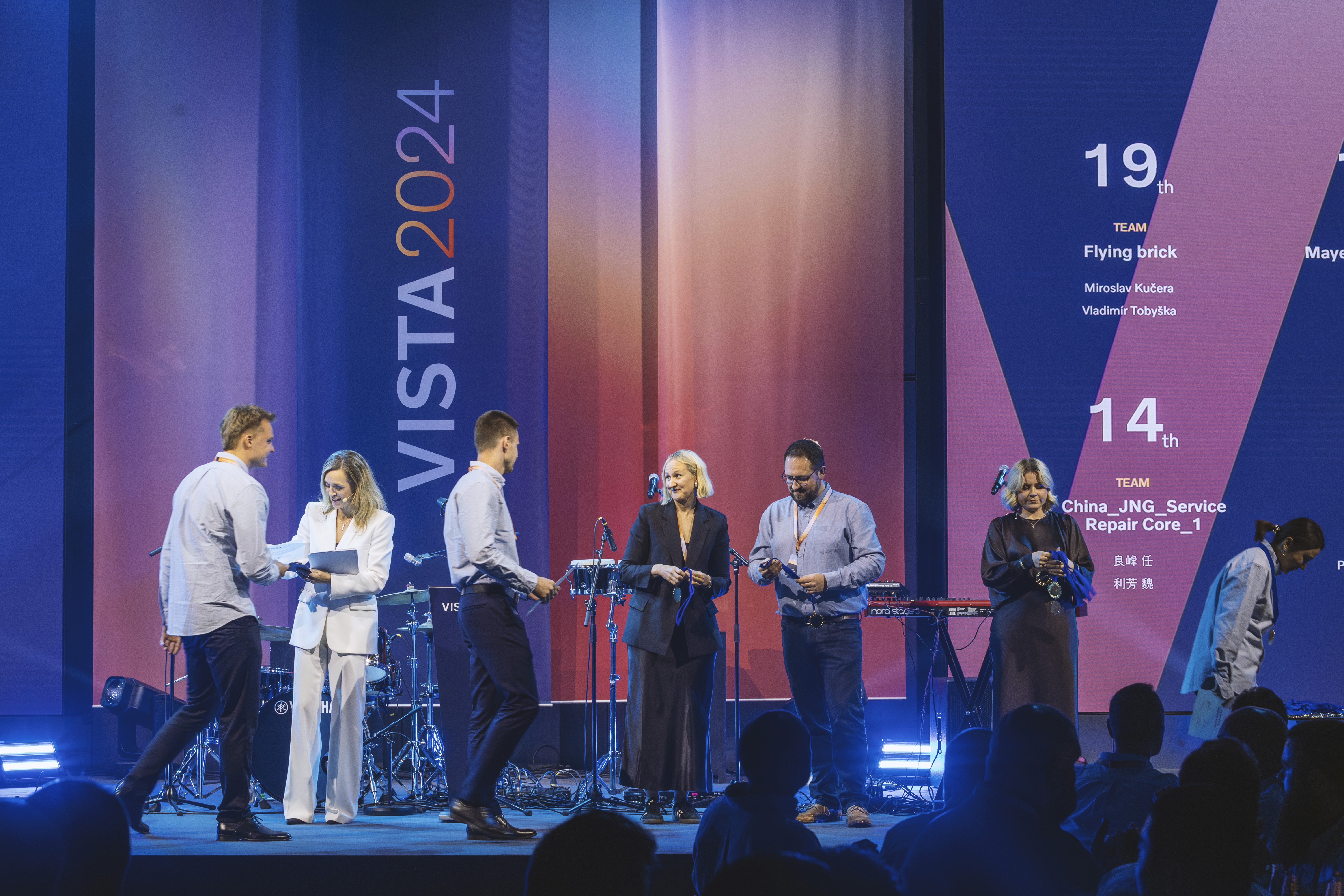 En presentatör står på en scen framför en stor publik med en stor bild av planeten jorden som hänger från taket