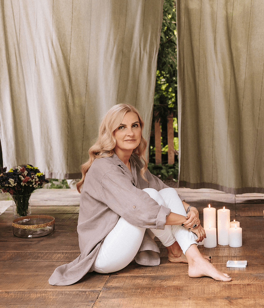 Beata Grala, psycholog, teraupetka, siedzi na drewnianej podłodze i patrzy na odbiorcę/odbiorczynię