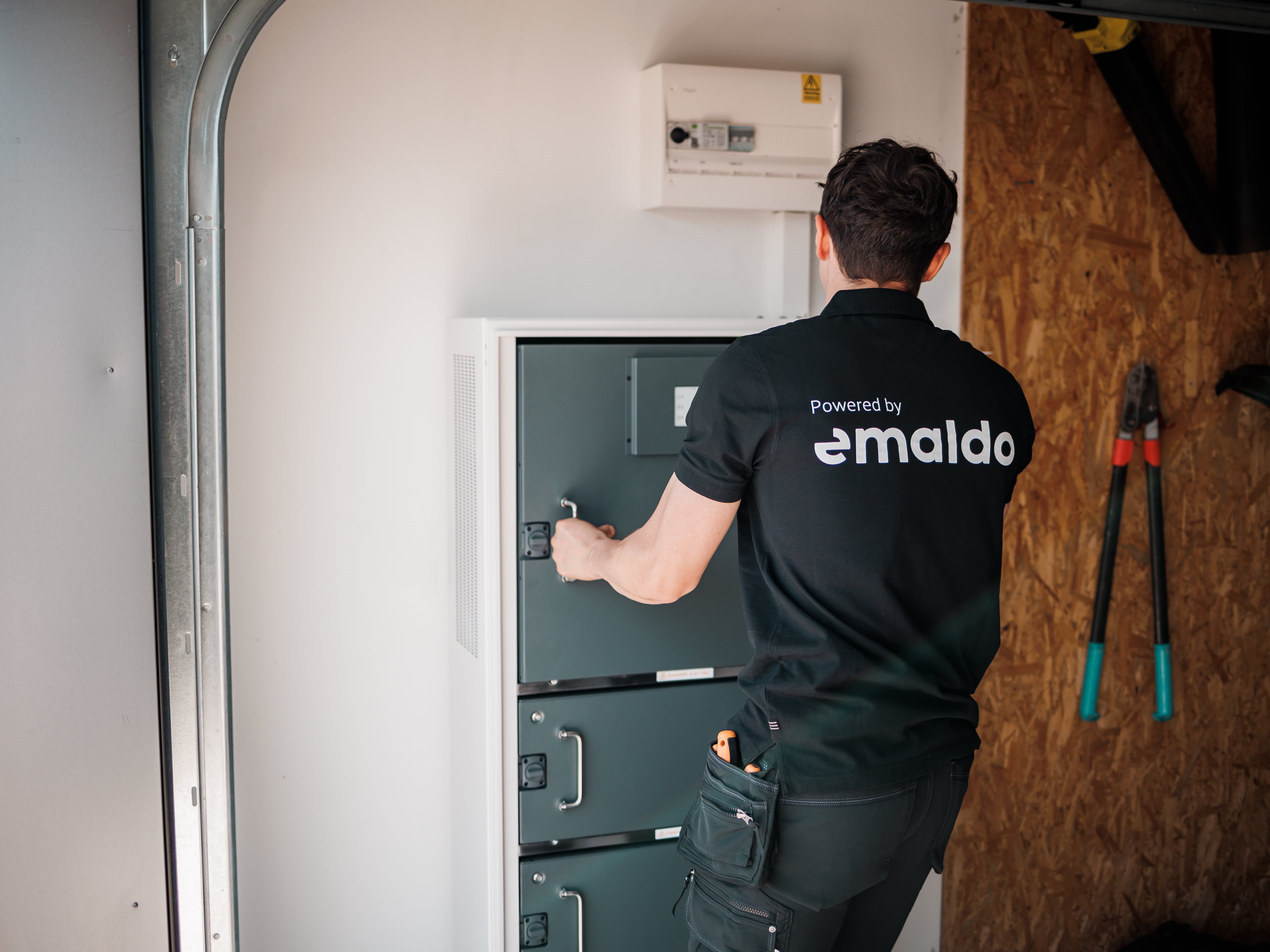 A winding road cuts through rocky terrain, surrounded by patches of green grass and illuminated by sunlight.