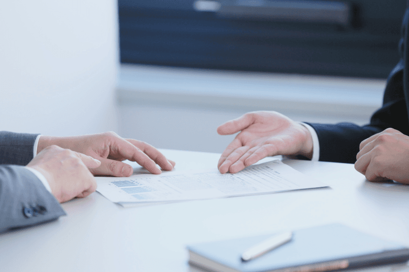 a hand holding a white business card against a purple background