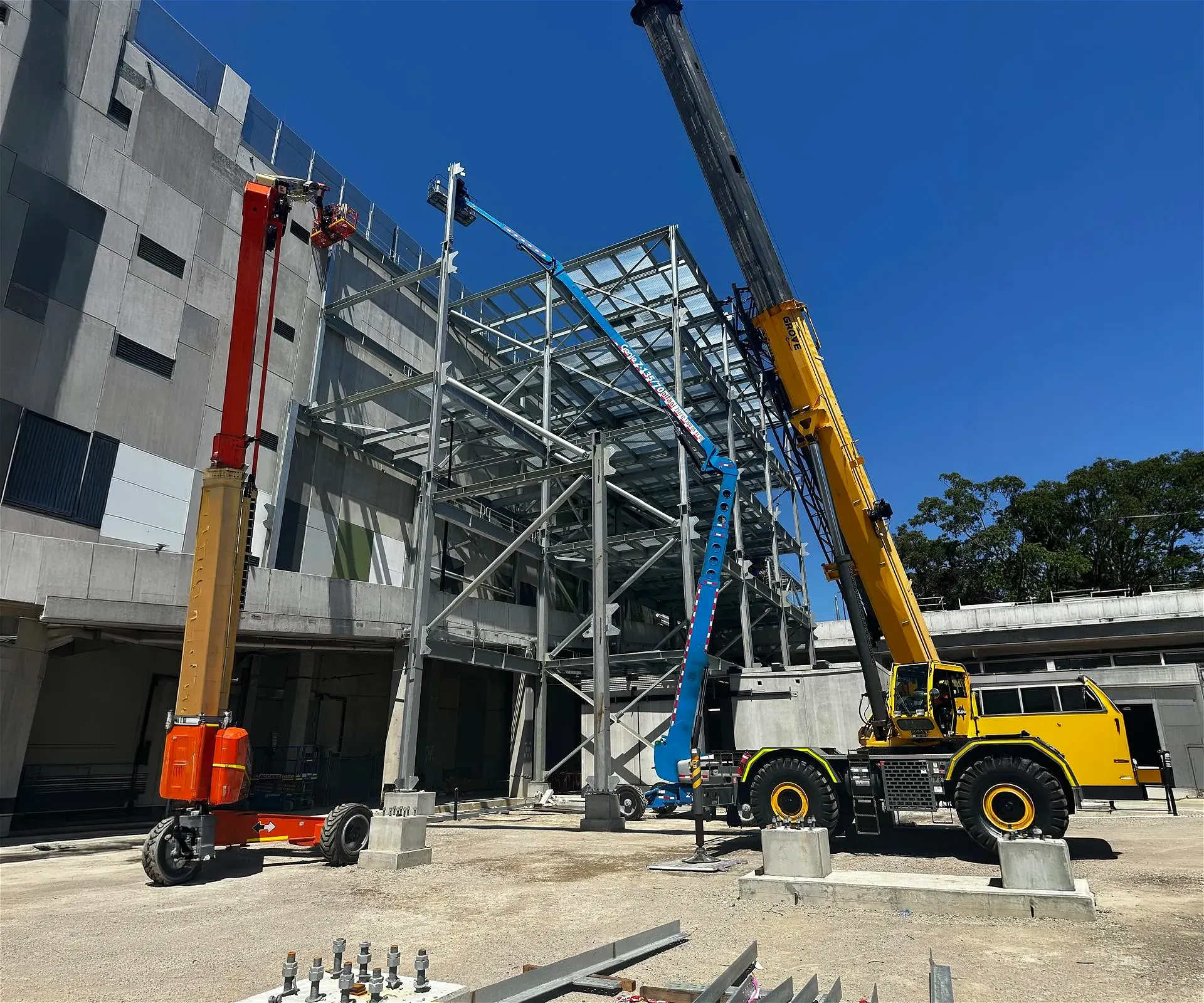 Construction site with cranes and boom lifts building structure