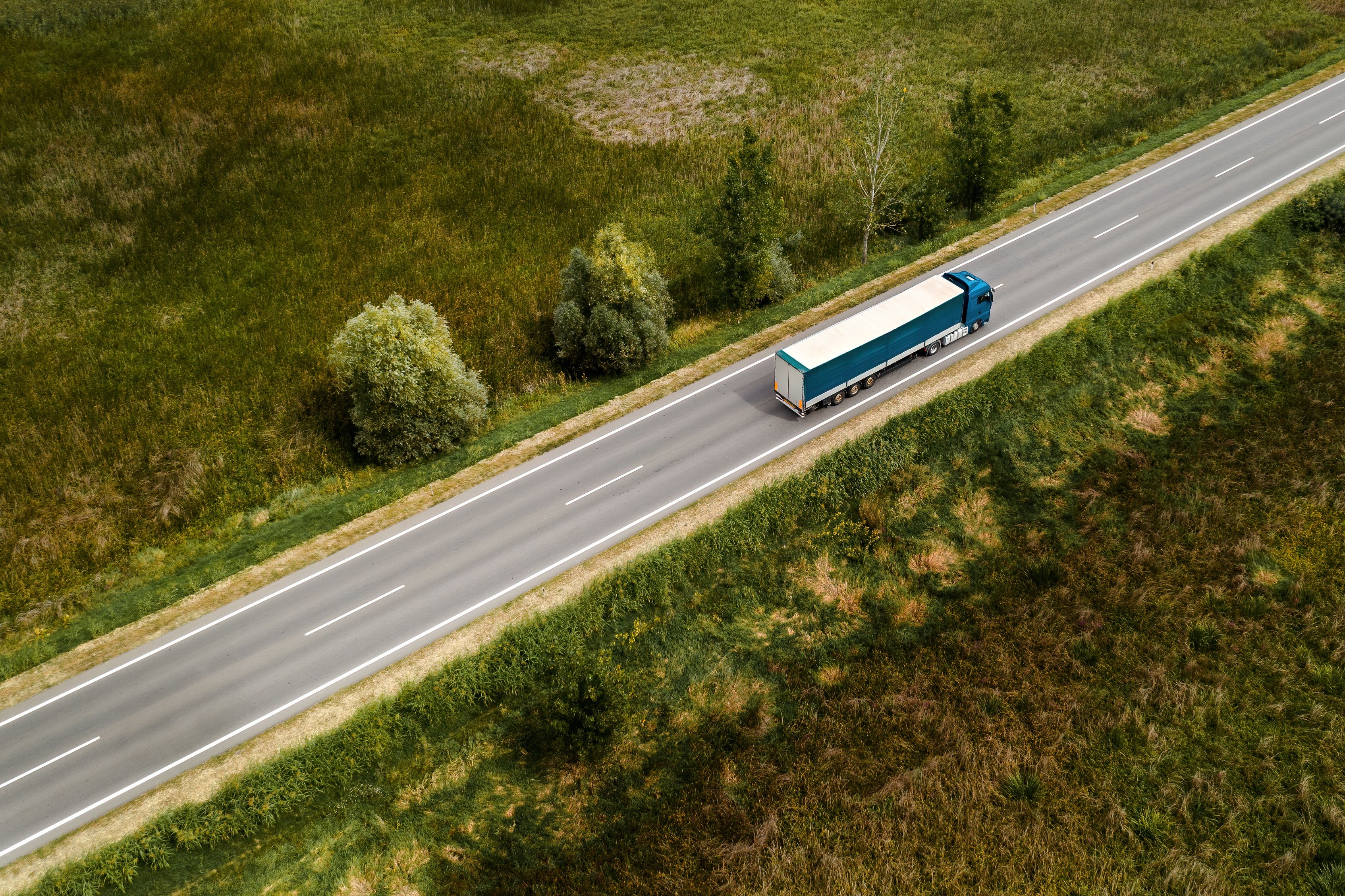 White truck driving on a road through fields