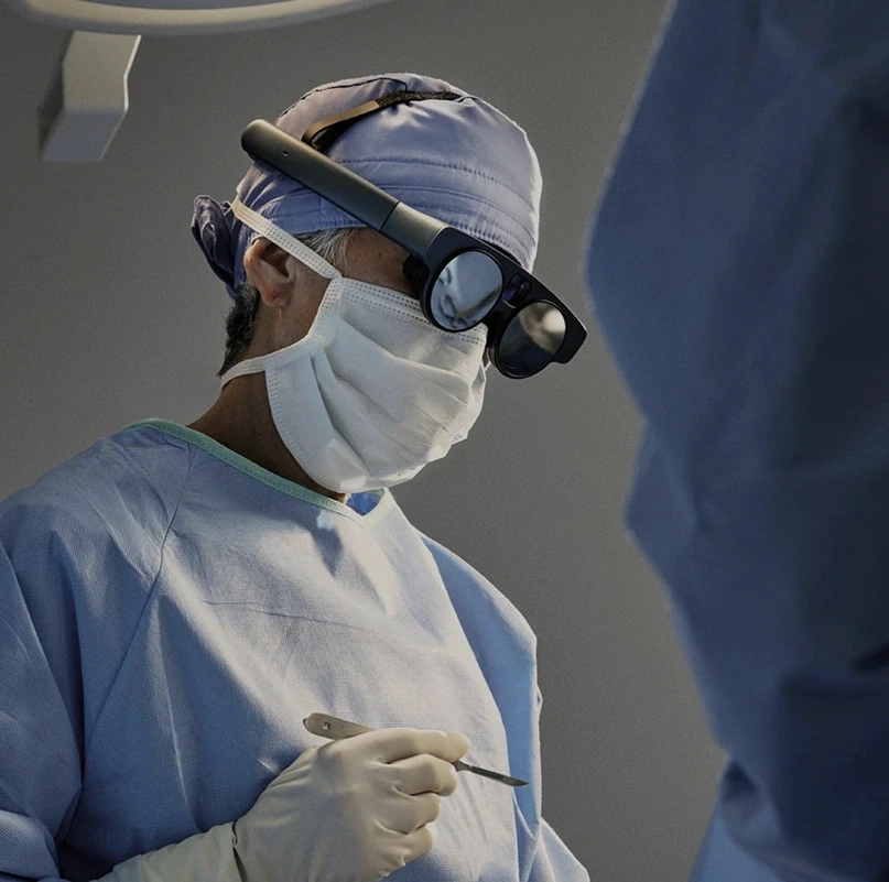Surgeon wearing Magic Leap 2 AR smart glasses during a procedure in an operating room