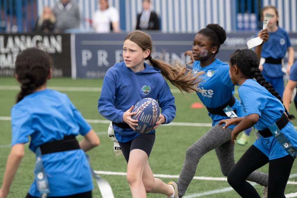 person holding pair of blue New Balance cleats