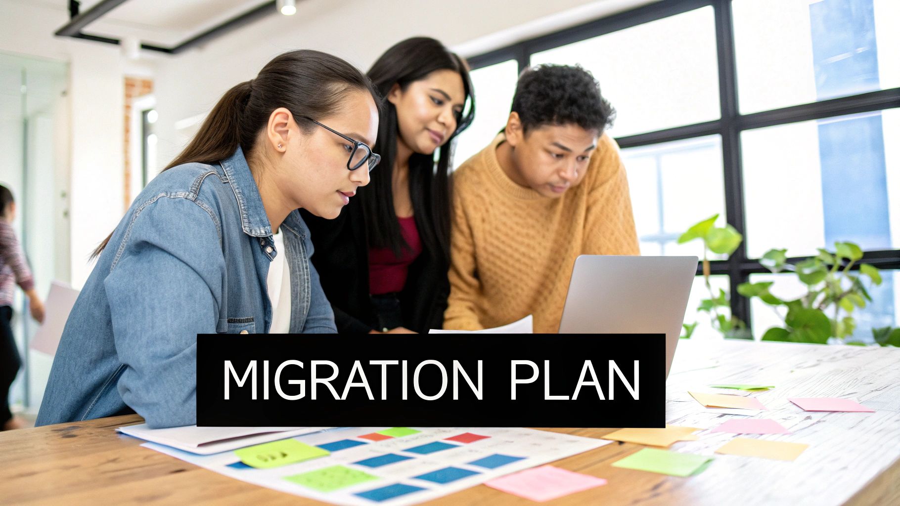Three young professionals reviewing a migration plan on a laptop during a collaborative meeting in an office.
