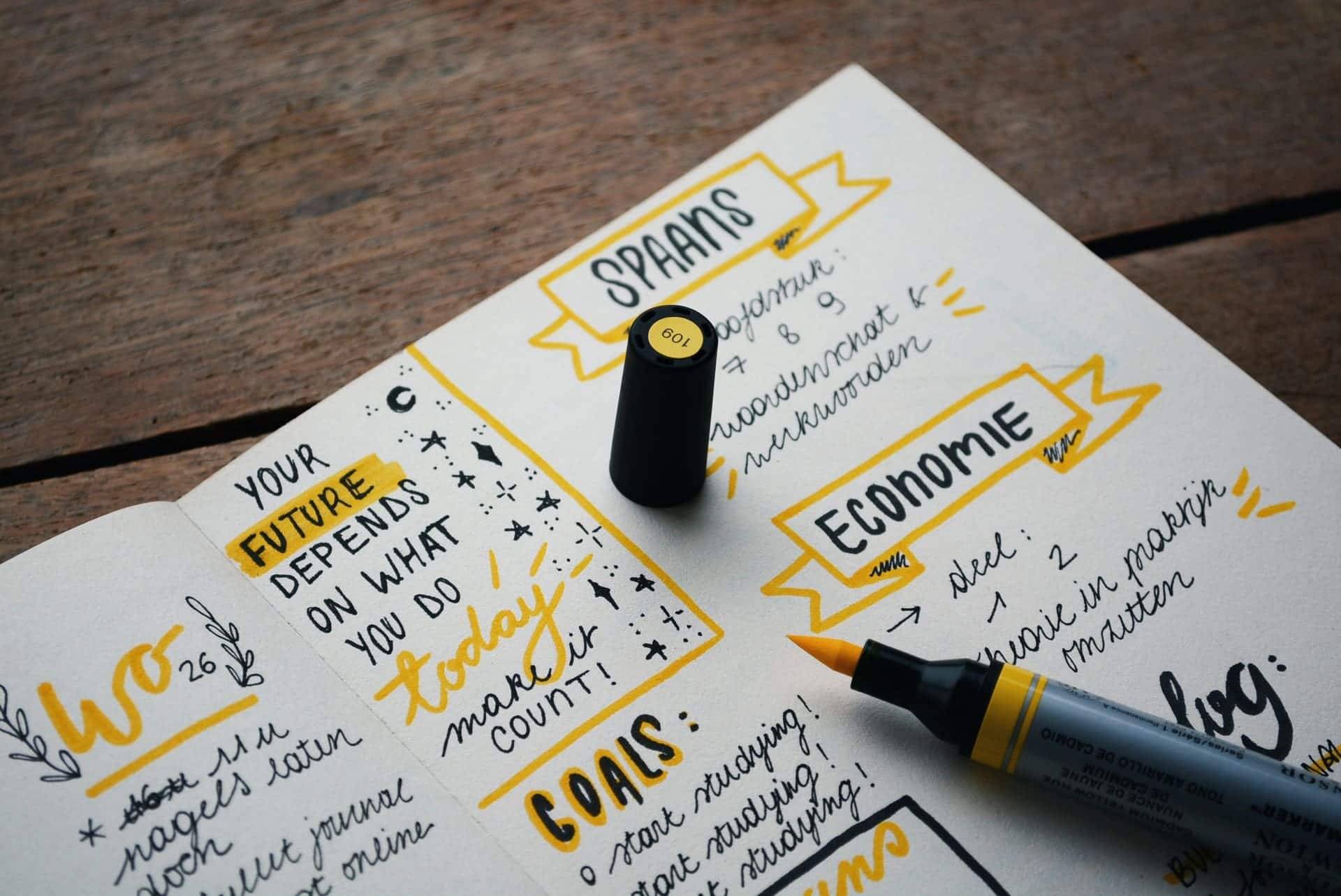 Bullet journal with motivational quotes and yellow marker on wooden table.