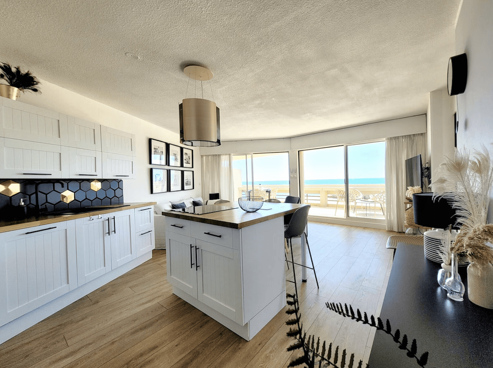 Modern staircase with wooden steps and black railing, decorated with hanging gold lights. Bright white walls feature abstract art, creating a sleek, airy ambiance.