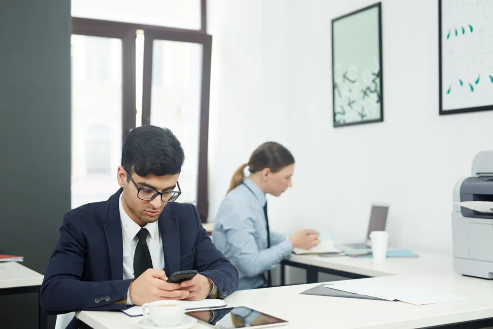 man at desk looking at phone