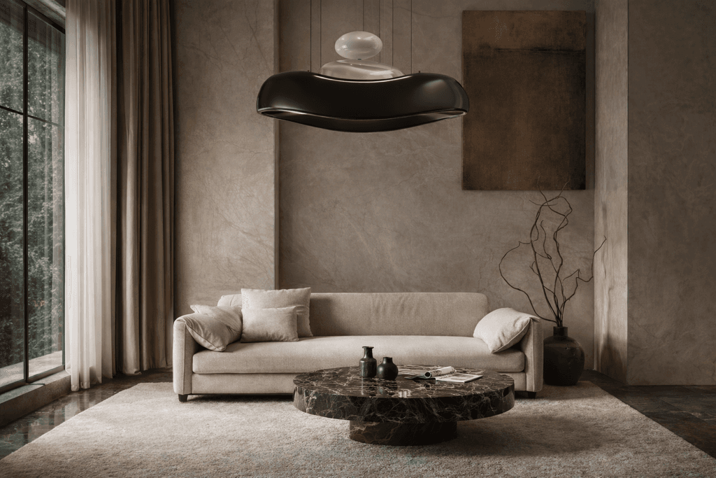 “Luxury contemporary living room featuring a sculptural black designer pendant light suspended above a cream sofa and marble coffee table, showcasing statement lighting design and premium modern interior styling.”