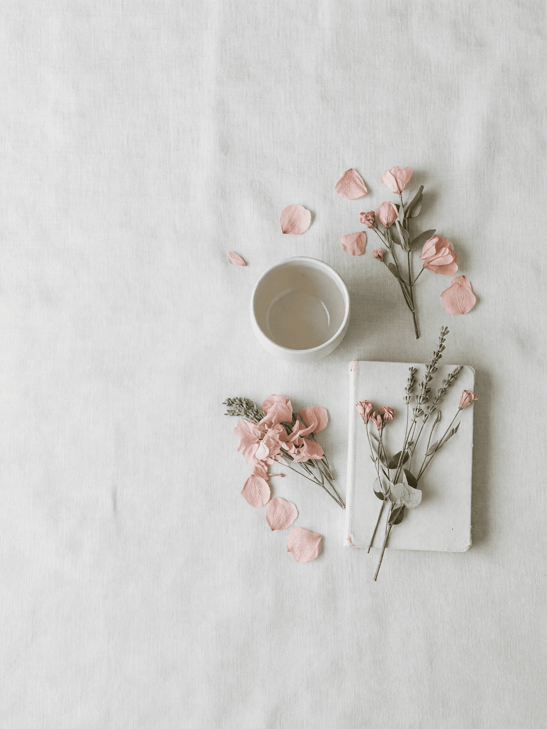 Pastel flat lay with a linen cloth, ceramic cup, dried flowers and notebook in blush pink, sage green and cream, generated with Grok Imagine in Atlabs