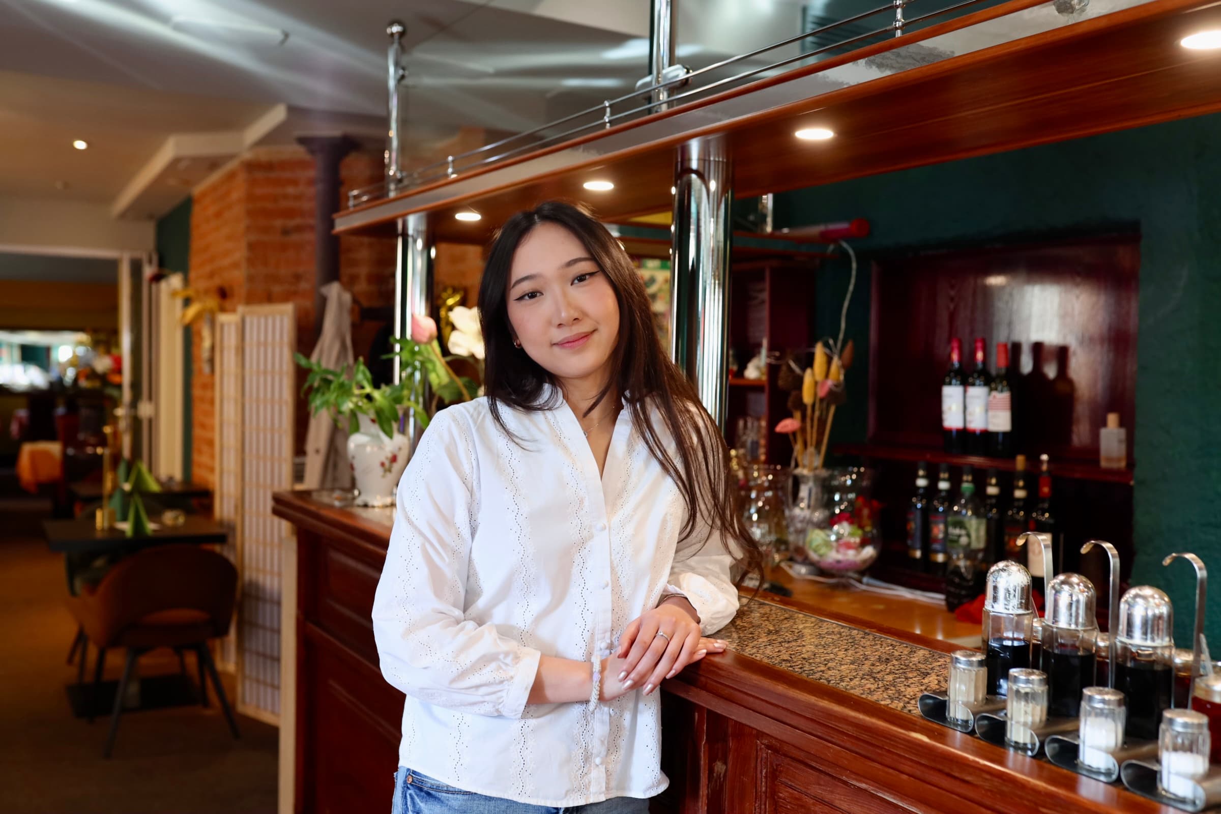 Junge Frau im Restaurant, lächelnd an der Bar. Restaurantbesuch.