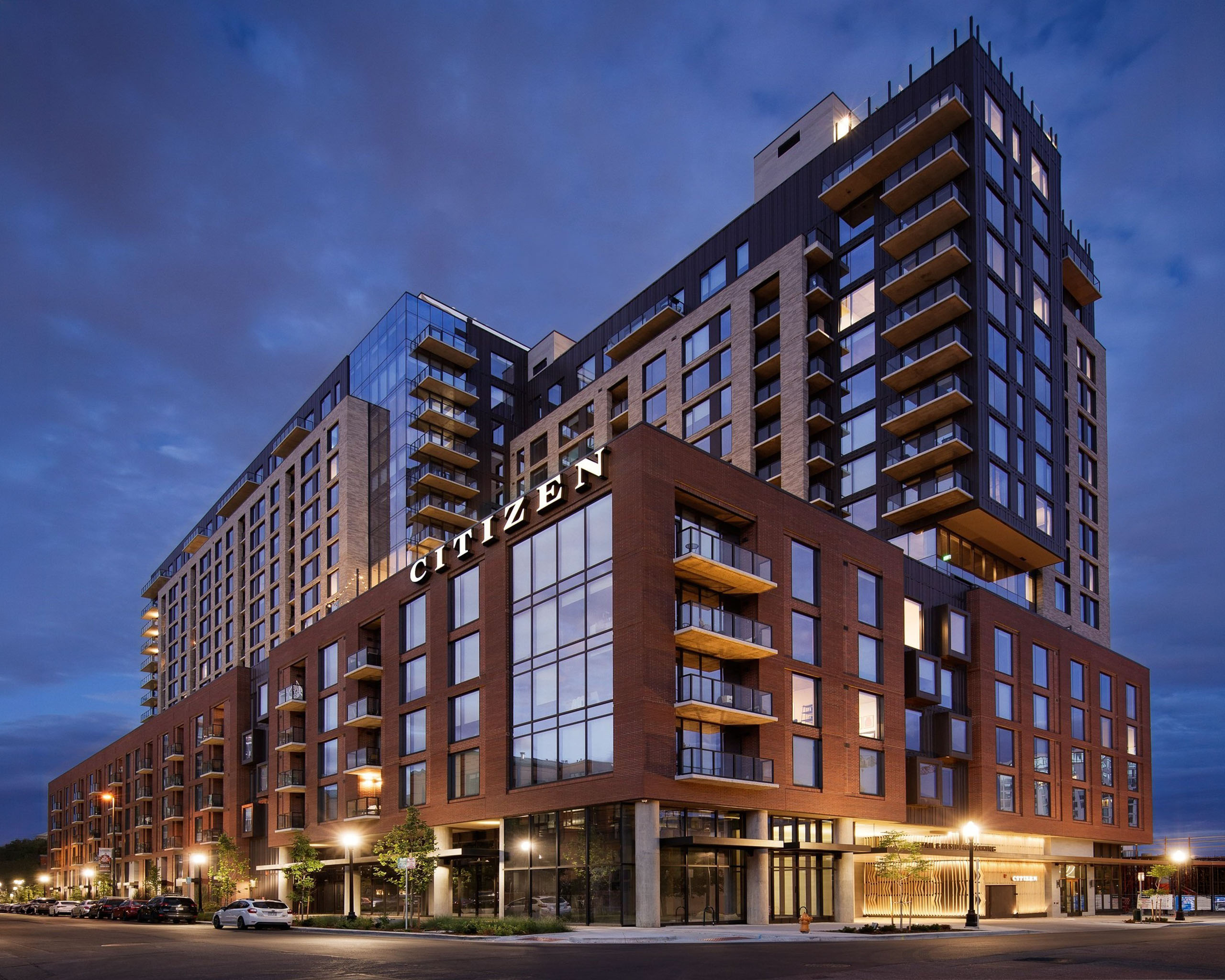 Modern apartment building with glass and brick facade at dusk.