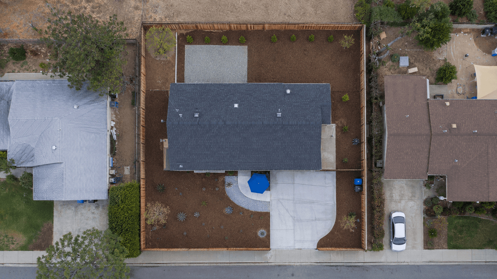 An aerial view of a modern modular home on its lot, showing property boundaries and neighboring parcels.