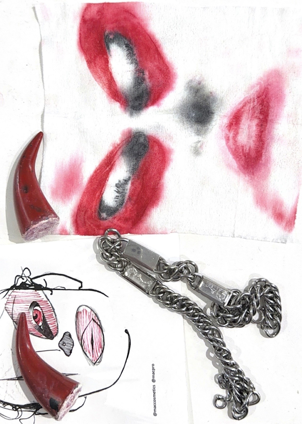 Bo Quinn process board with a red face-wipe print, sketch, horn props and silver chain
