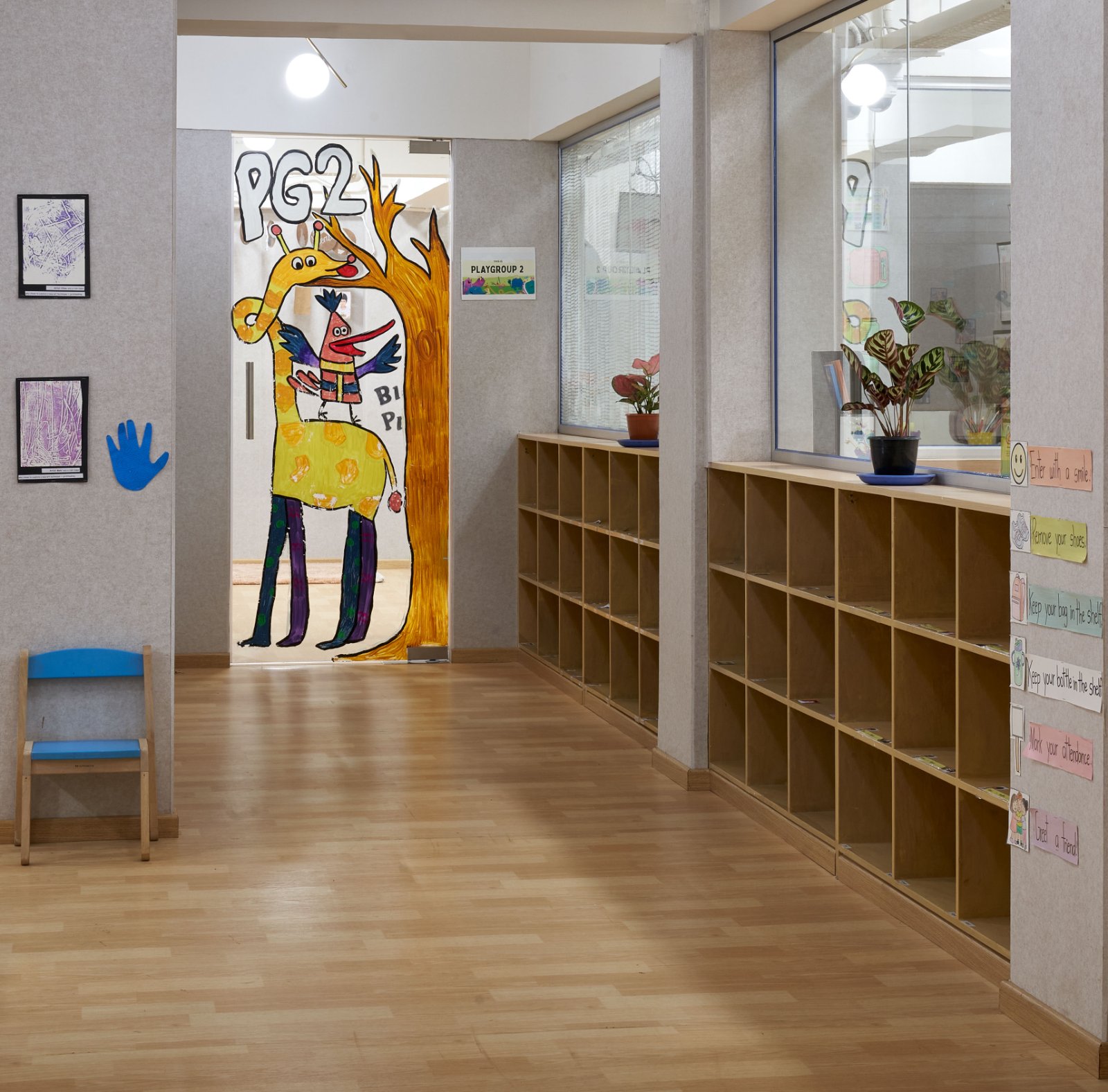 Nature-inspired preschool entrance with sculptural tree partitions and suspended green leaf ceiling panels.