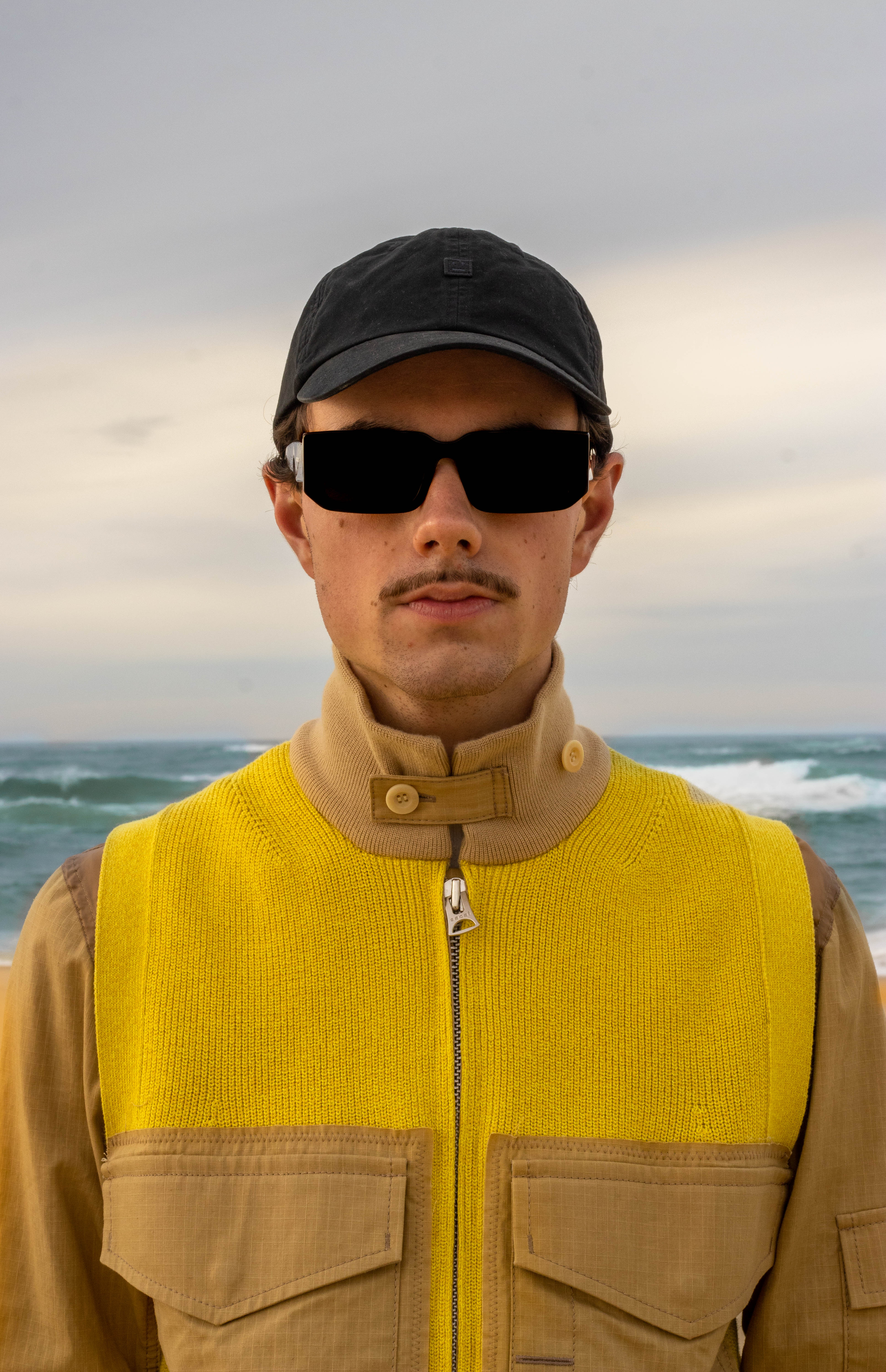 shooting masculin nature proche de l'océan, une tenue jaune très vif qui contraste avec le blue de l'eau