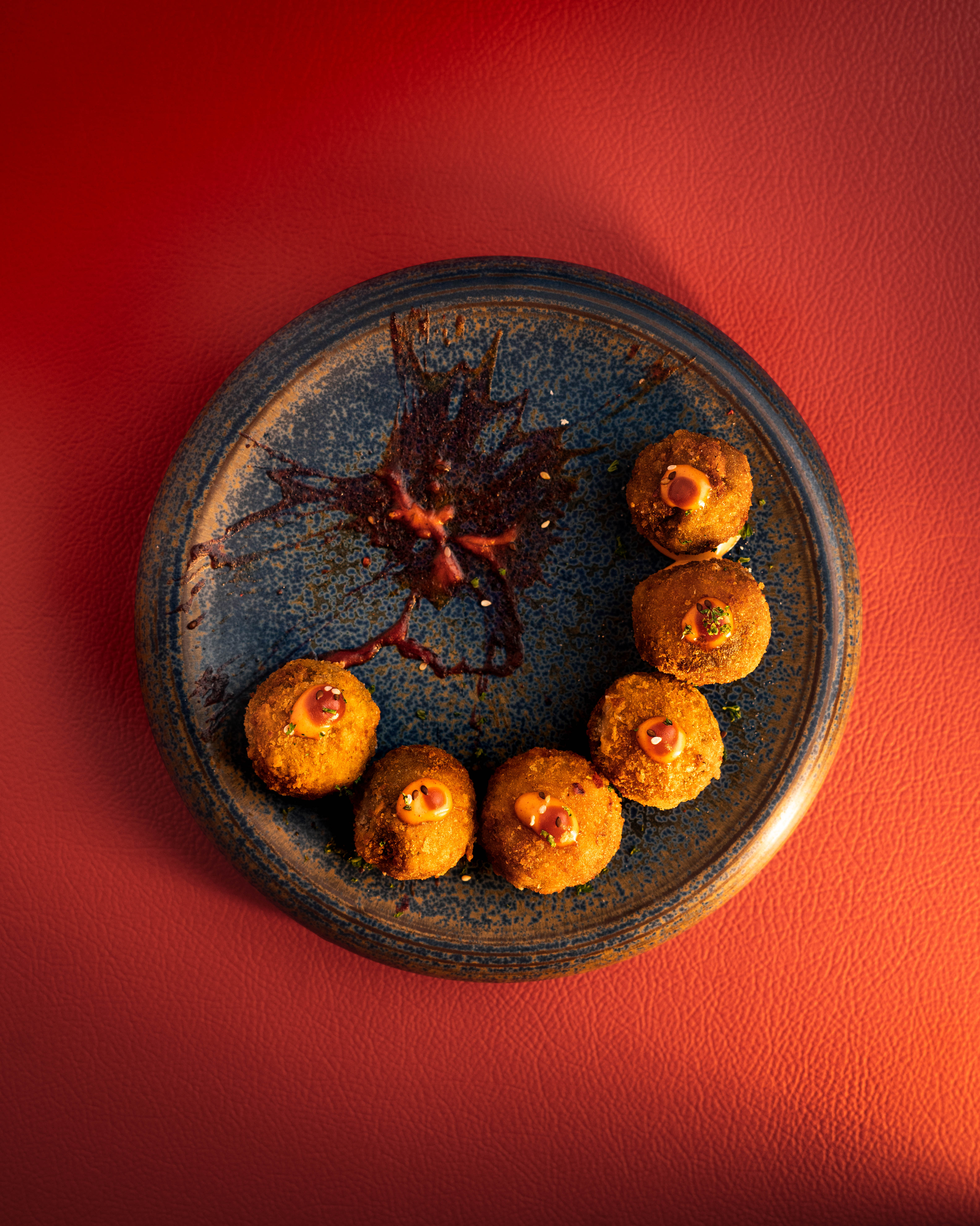 Plate with a seared salmon fillet topped with green herb garnish and sauce, served on a white dish placed on a dark green marble table beside a white candlestick.