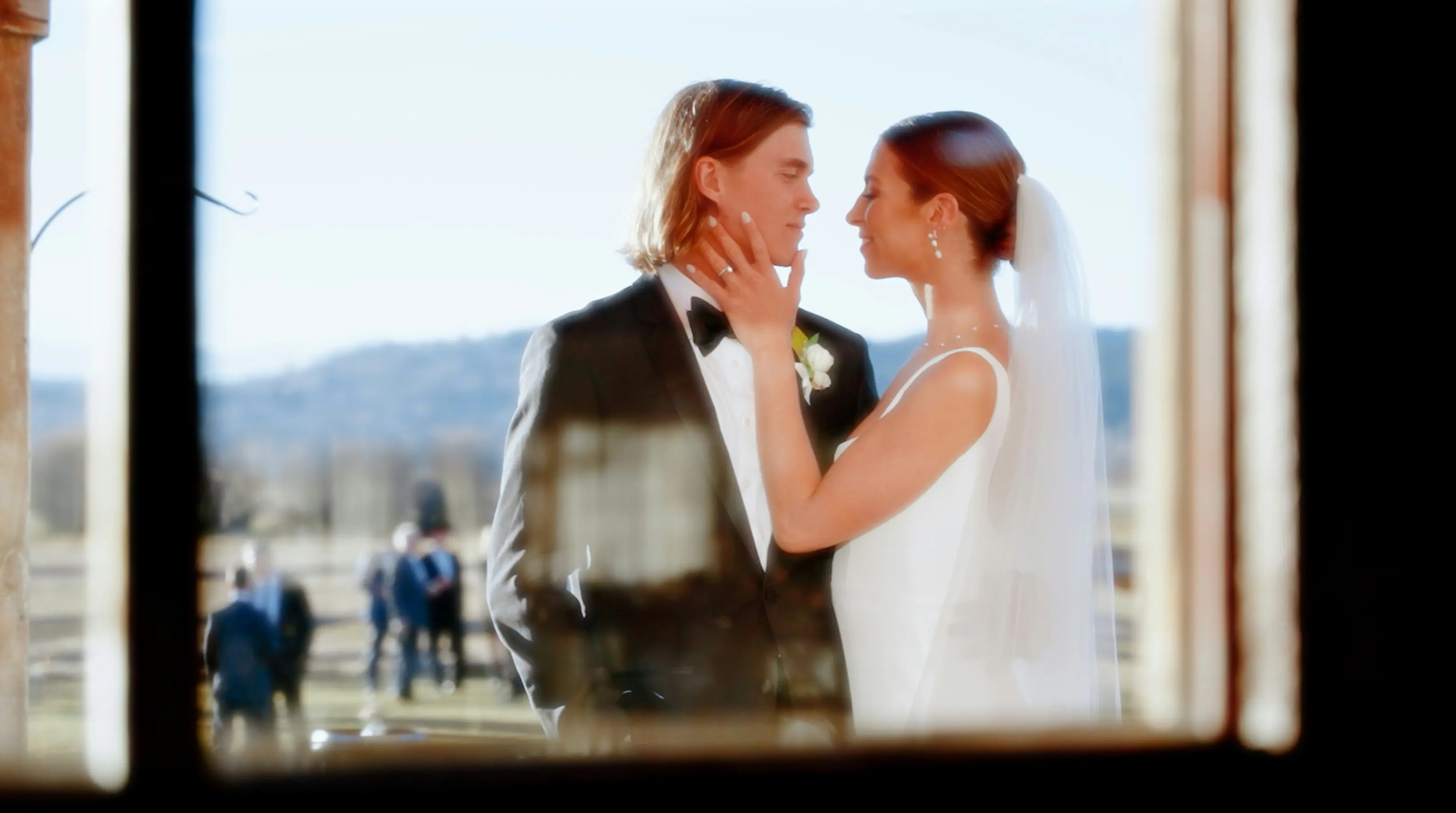 Emma and James having a romantic moment together, bride gently touching groom's face outdoors