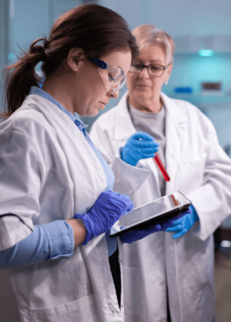 Silhouette of a researcher examining a slide under a microscope with a blue background.