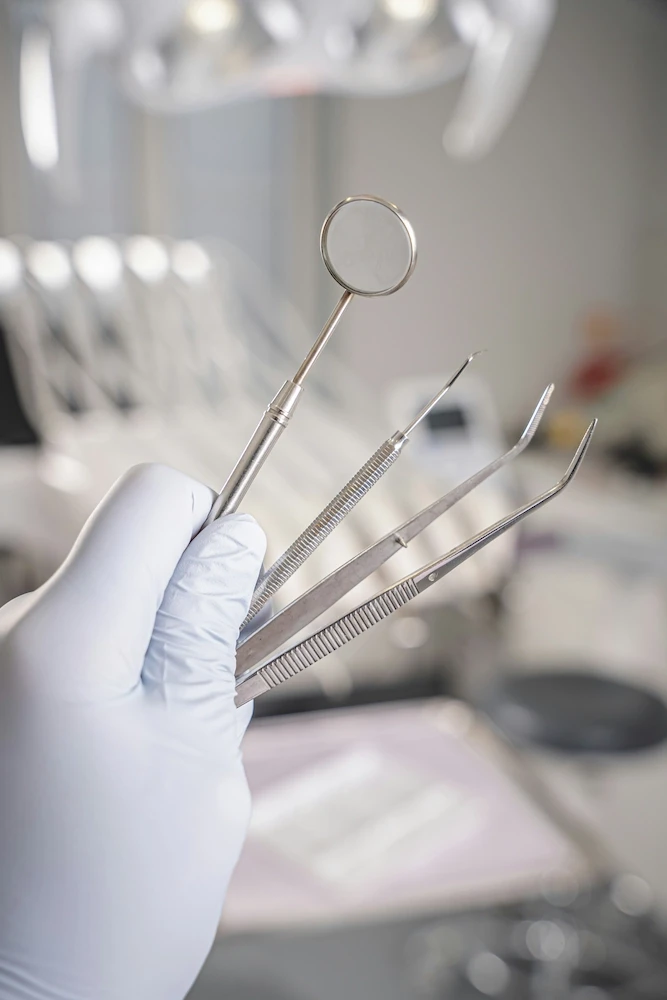holds dental instruments in gloved hand
