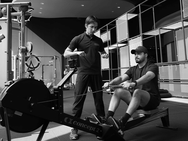 Man On A Rowing Machine With A Personal Training Coach