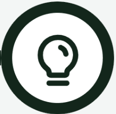 Smiling young woman with curly hair sitting at a laptop, in front of a teal wall.