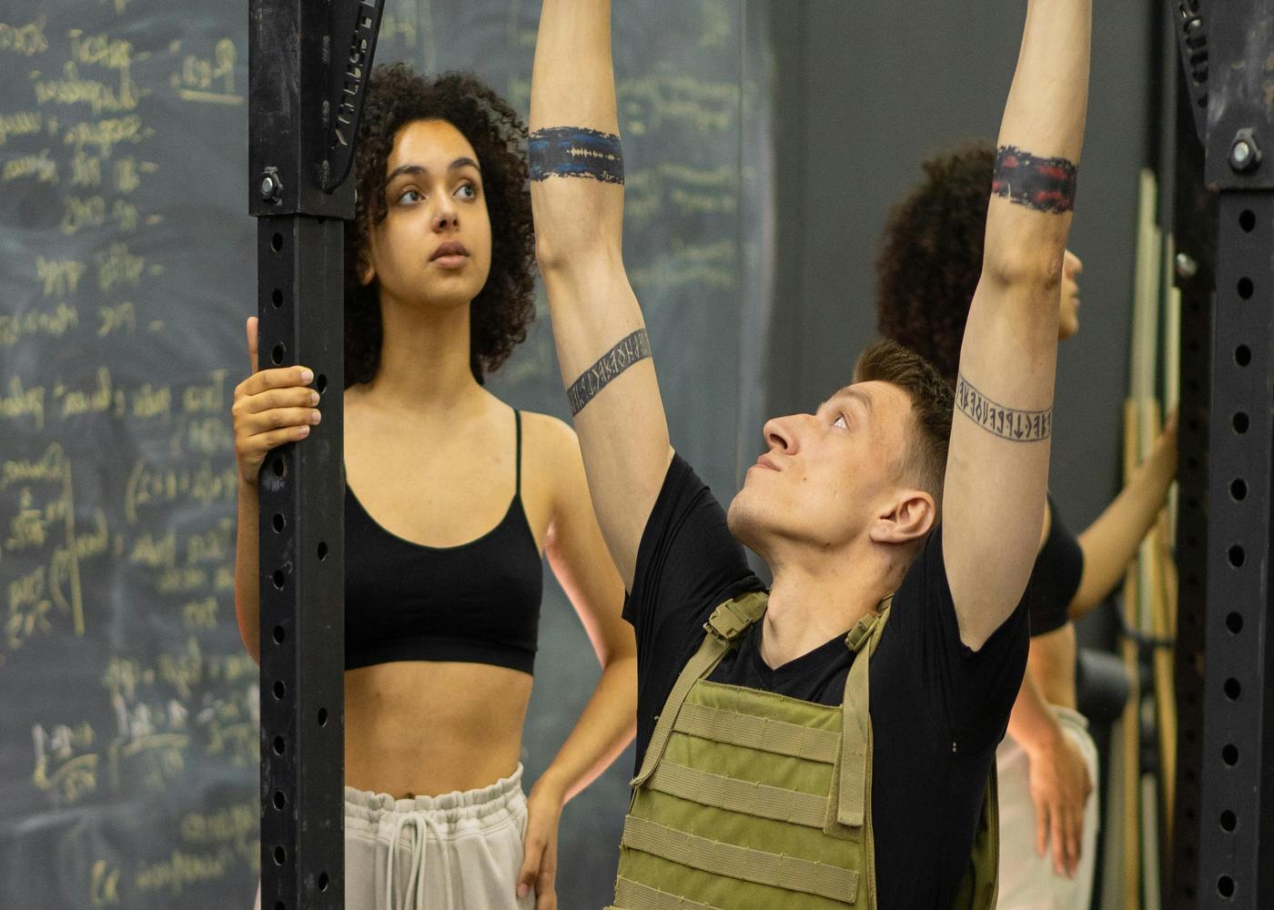 Woman watching military man hanging from pullupbar at the gym
