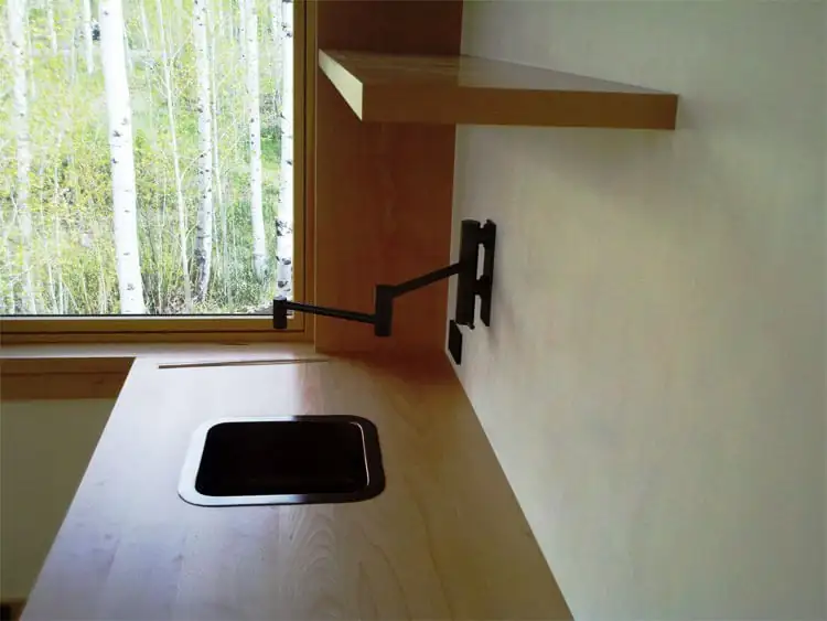 Bar sink with wall-mounted swing faucet beside a window