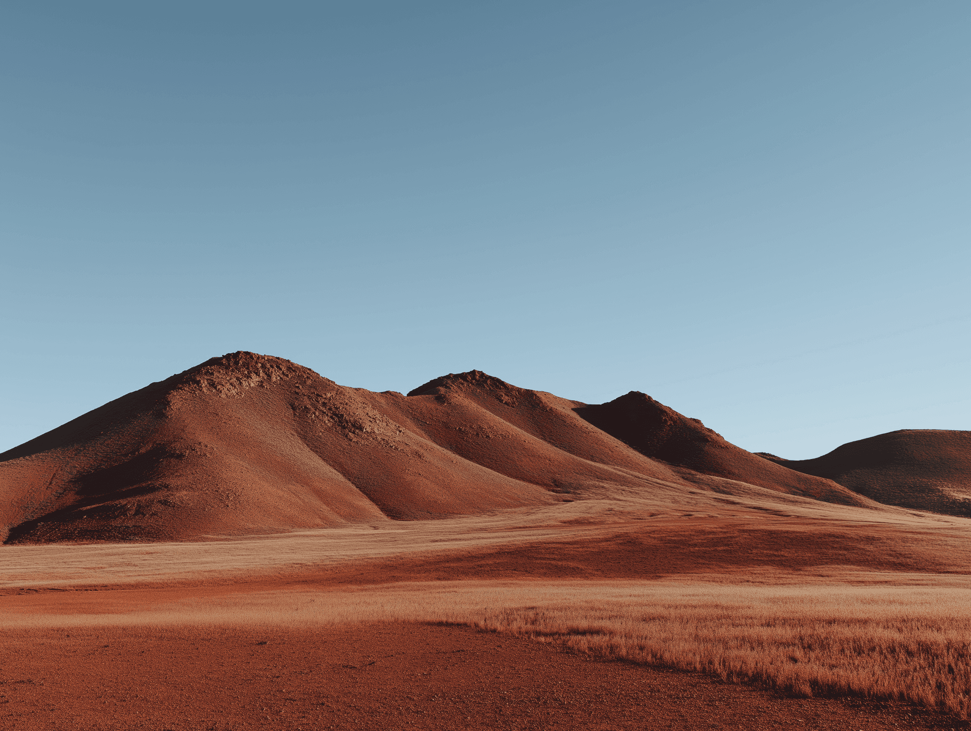 Red desert mountains under a clear blue sky