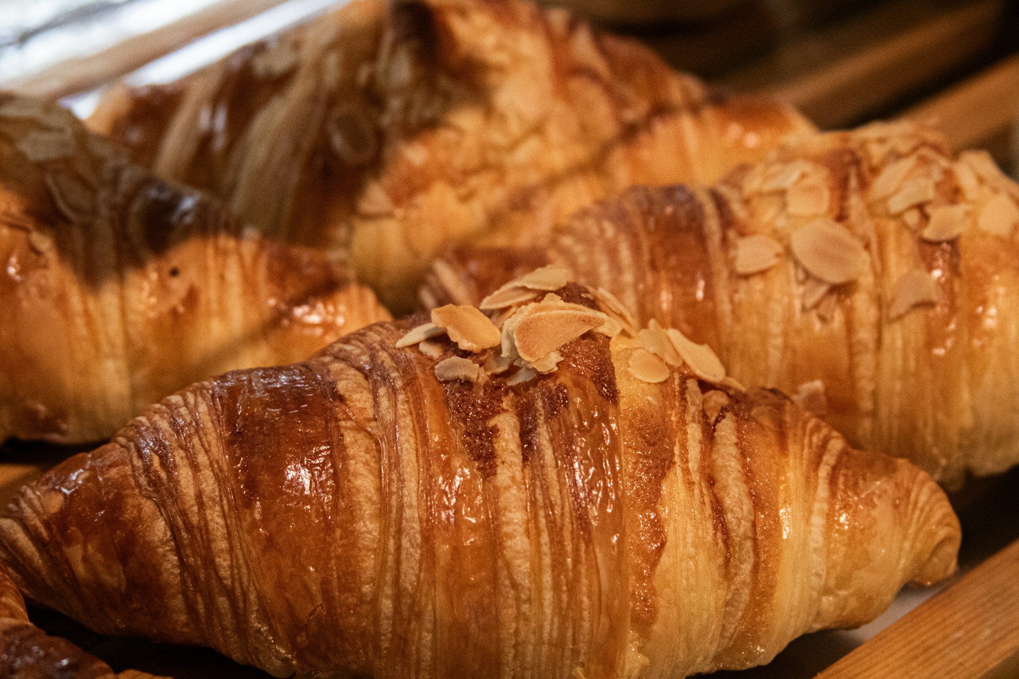 Almond croissants scattered with flaked almonds on a tray