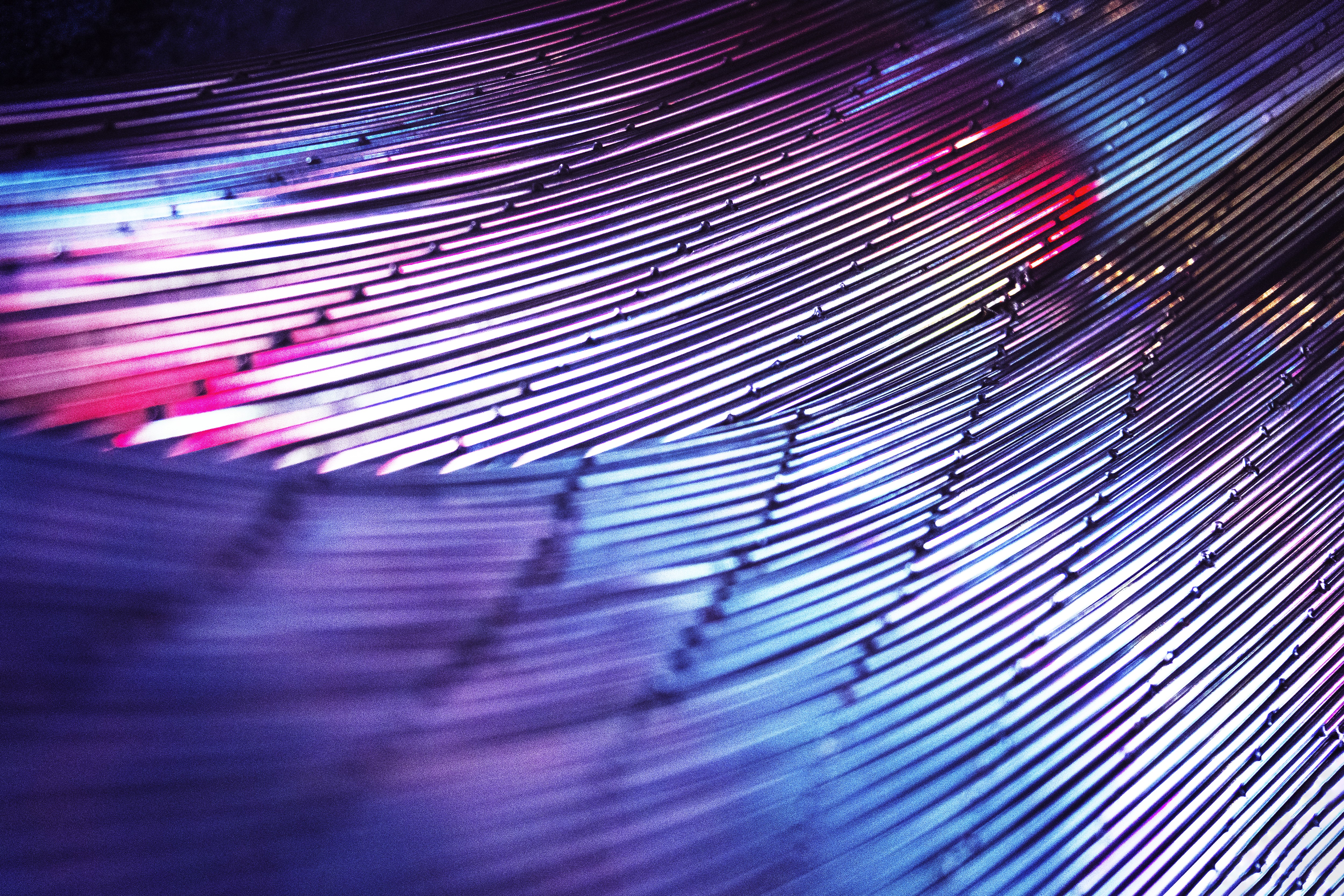 Abstract close-up of curved metallic lines with purple and blue lighting.