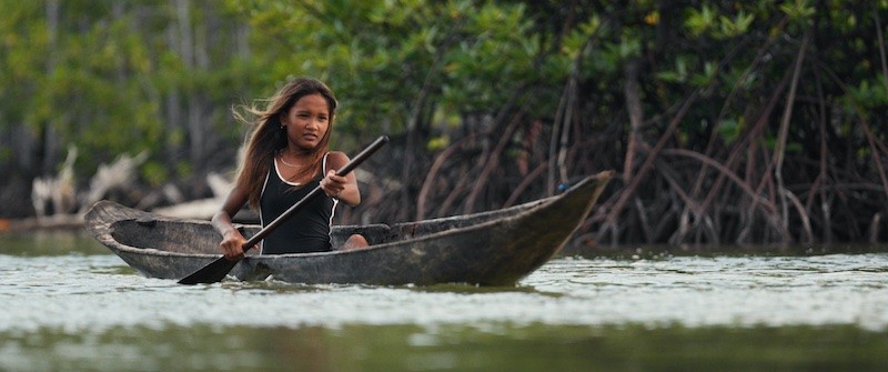 Indonesian girl in old wooden canoe