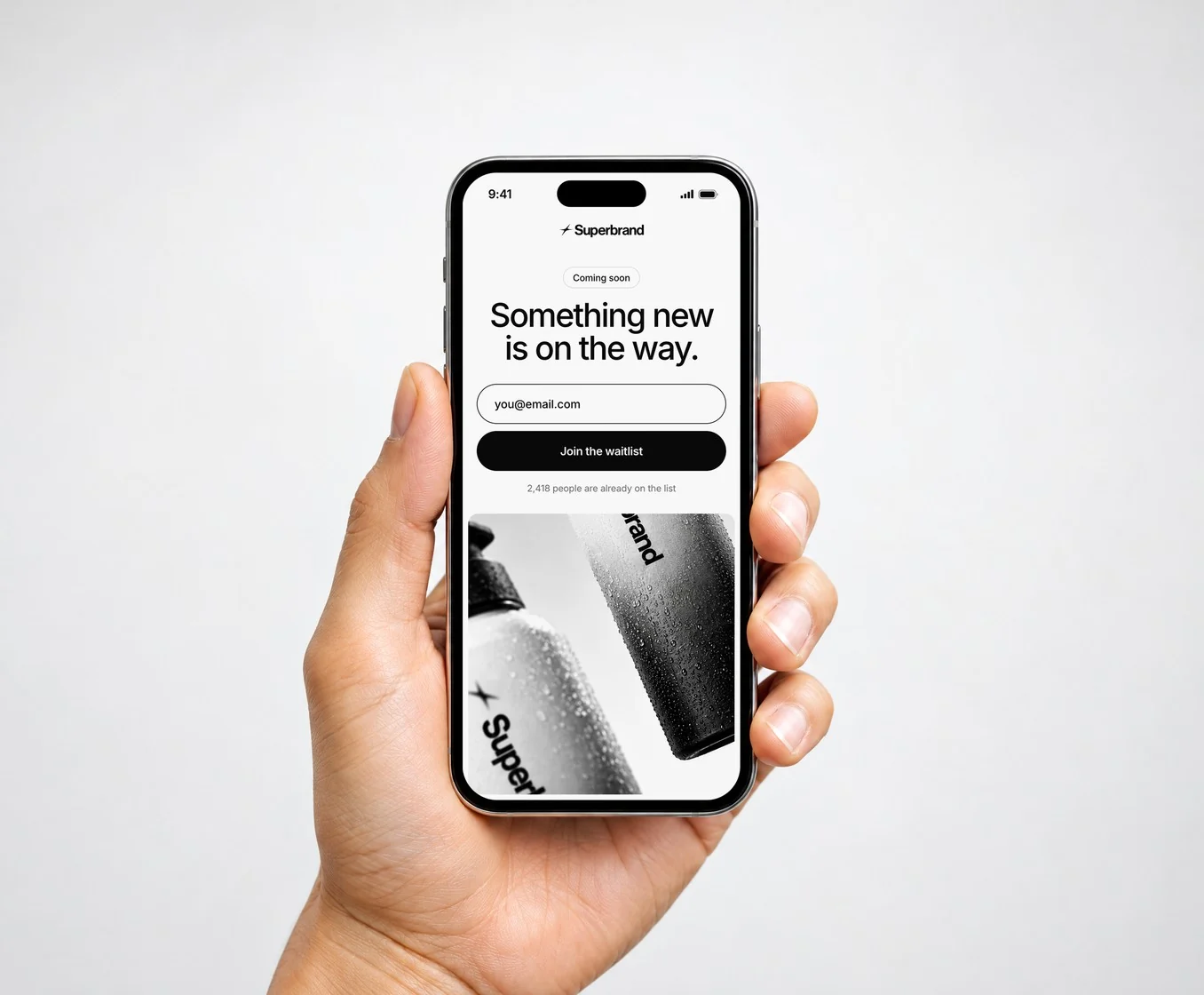 A hand holding a phone showing Superbrand’s waitlist sign-up: “Something new is on the way.”