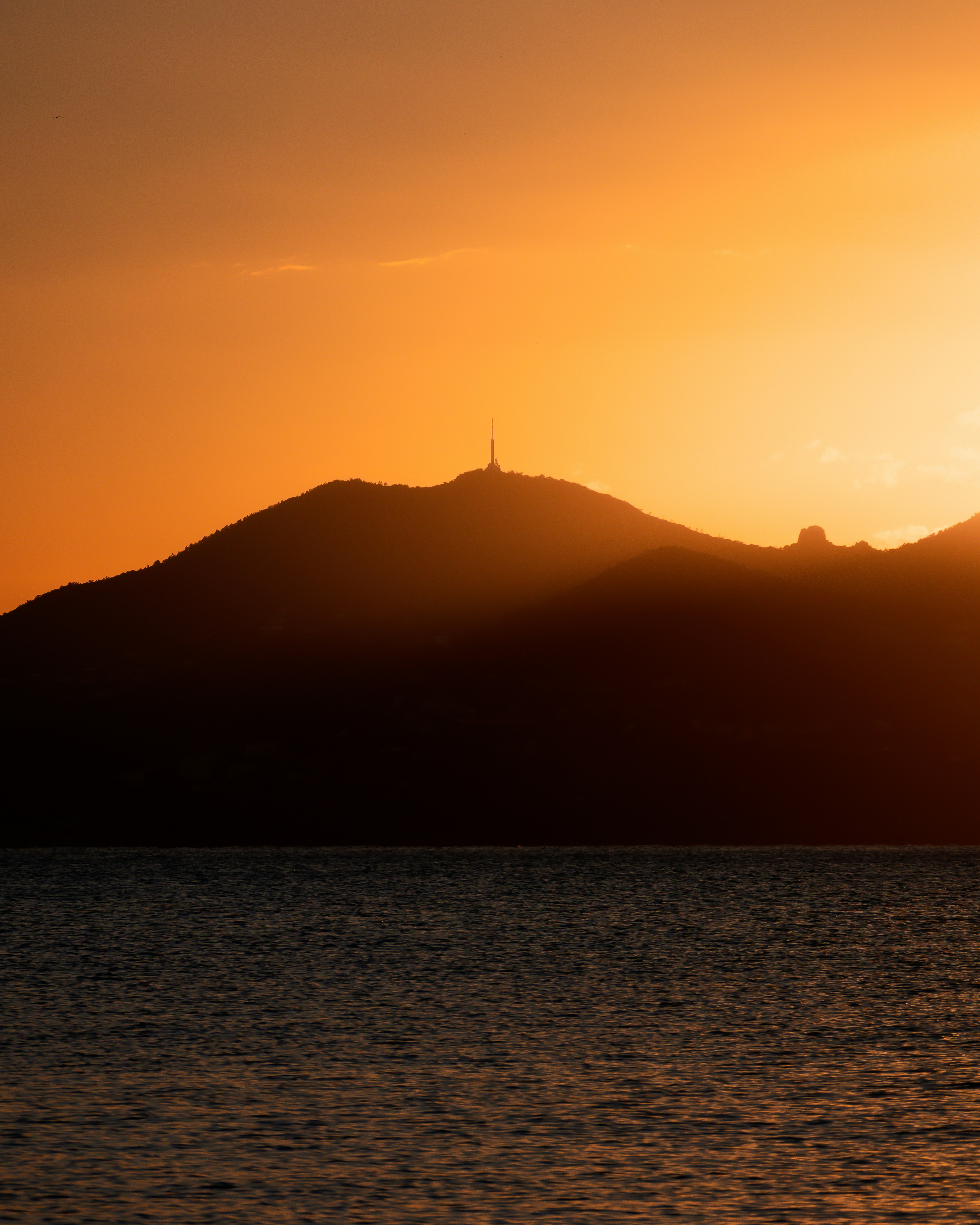 silhouette of hills and ocean at sunset