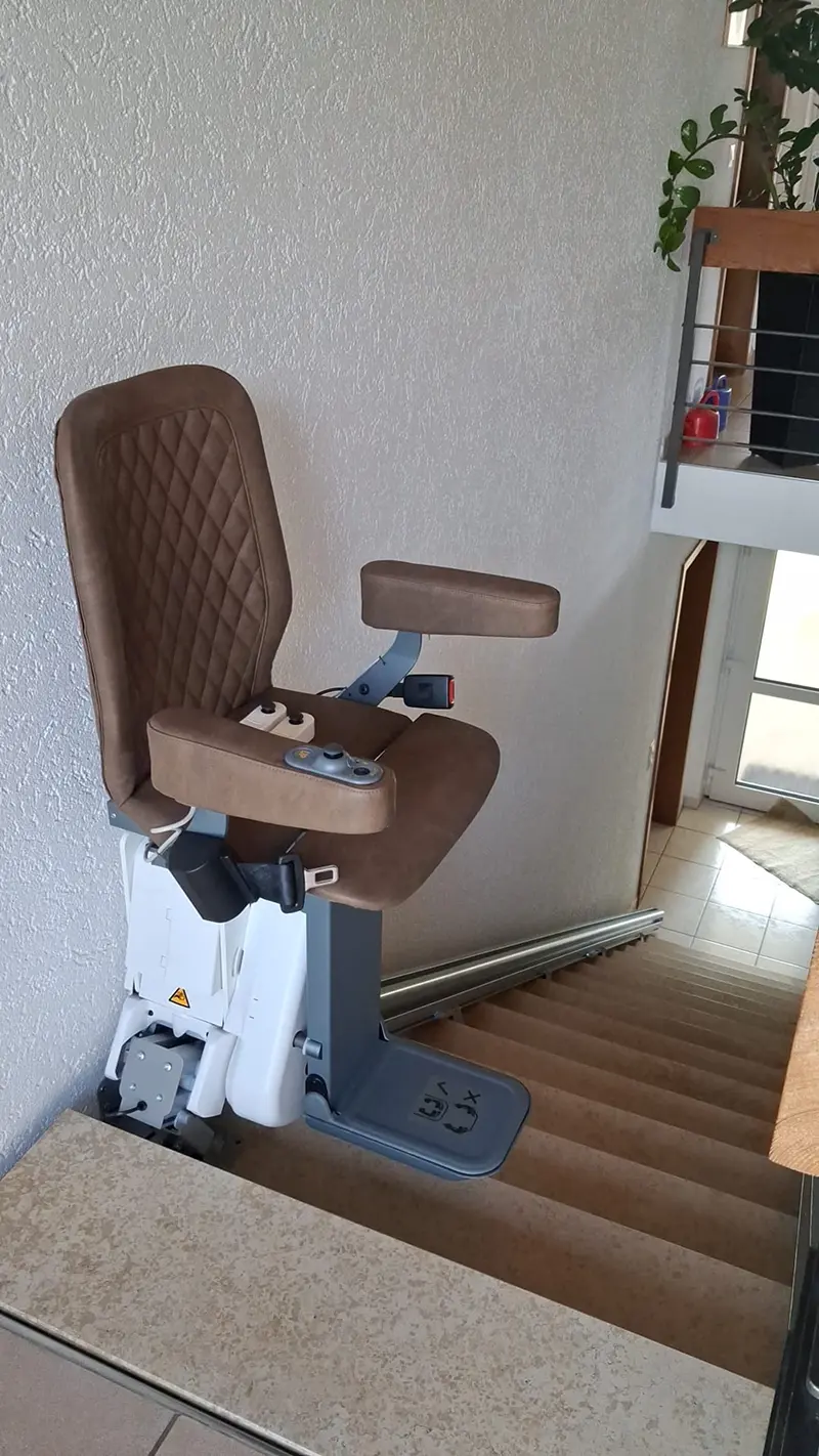 Treppenlift mit braunem Polstersitz an einer Innentreppe