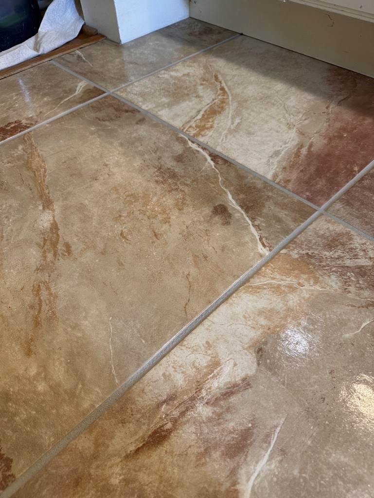 Tiled floor with marbled patterns and grout lines seamlessly cleaned, restored, and color sealed by Better Grout to complement the tile’s natural design.