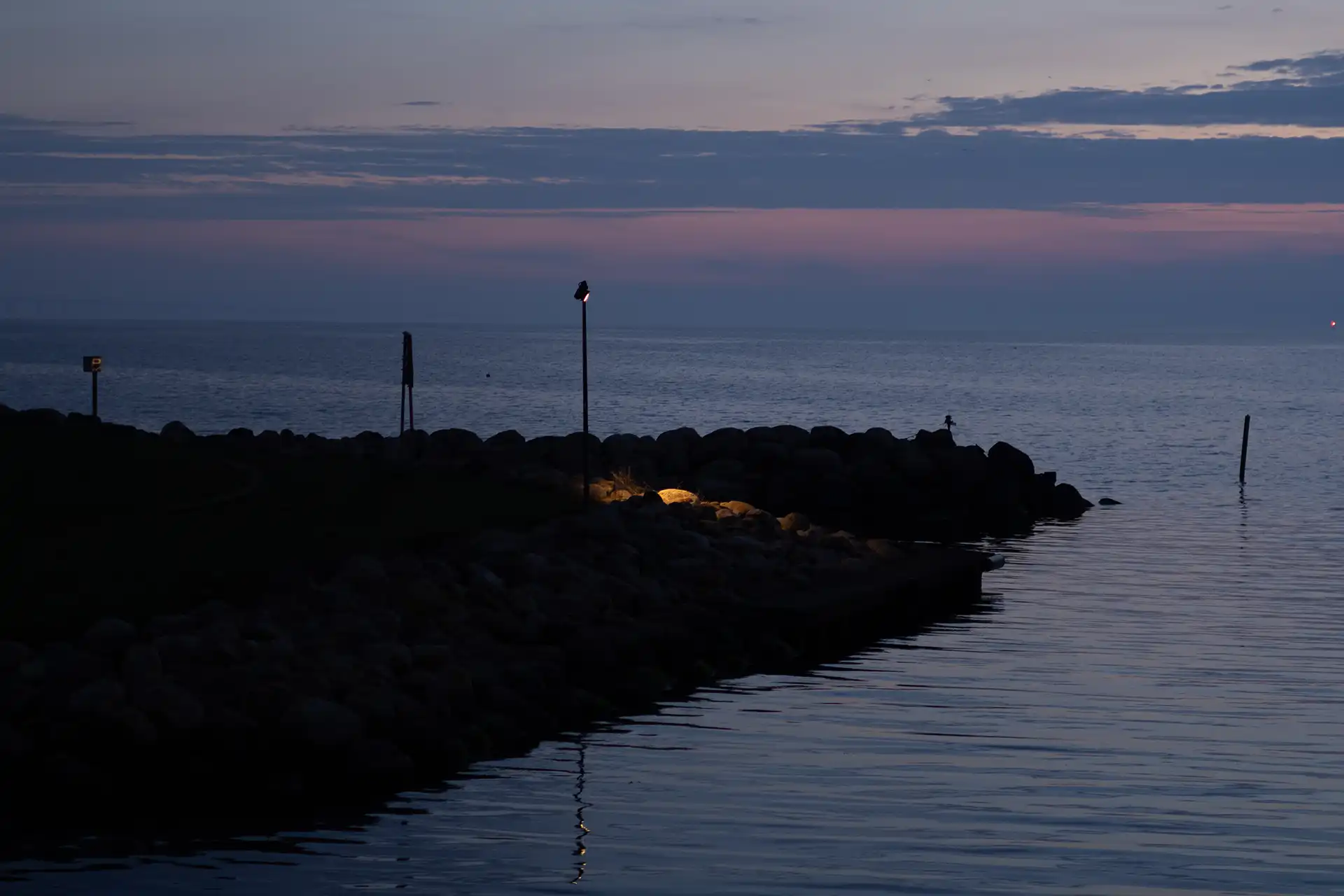 Land stretching into sea with a single lamp standing remotely