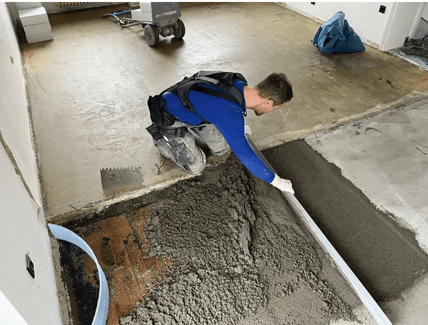 Travailleur utilisant un exosquelette de soutien du dos lors du nivelage de béton sur un chantier de construction