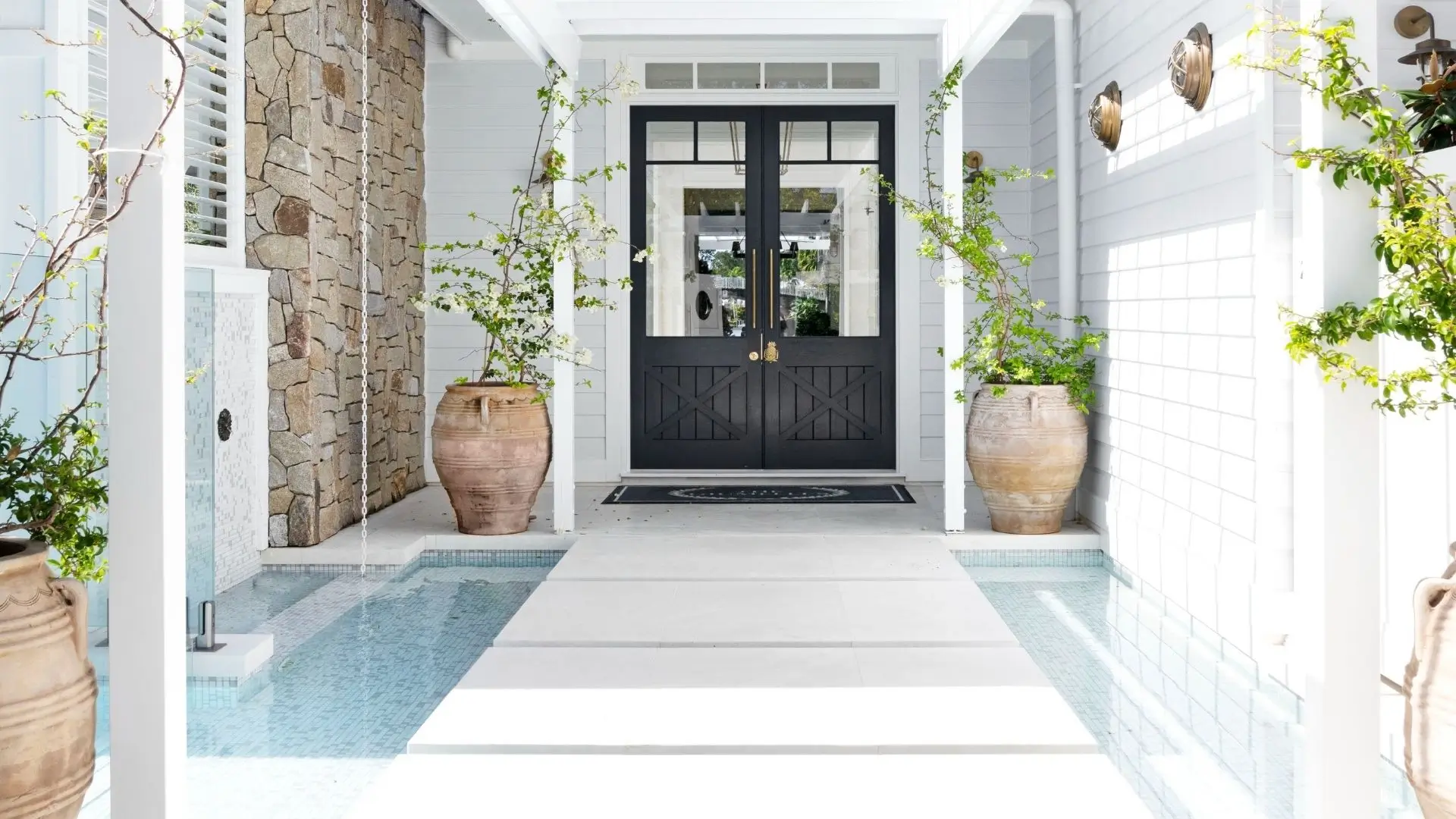 Entryway to the home with water feature and double doors with glass panels