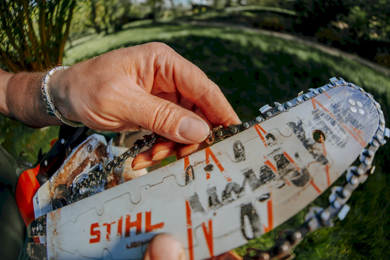 Nahaufnahme einer Hand, die eine Kettensägenkette überprüft. Kettensäge, Werkzeug für Holzbearbeitung, Reparatur oder Wartung.