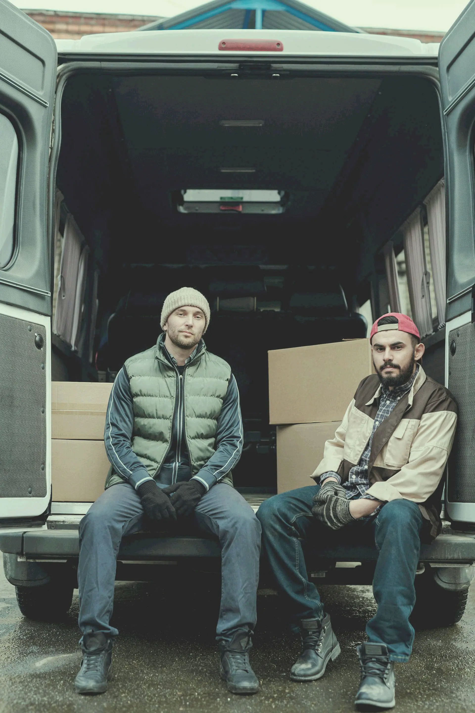 Photo of two moving workers sitting in the back of a van.