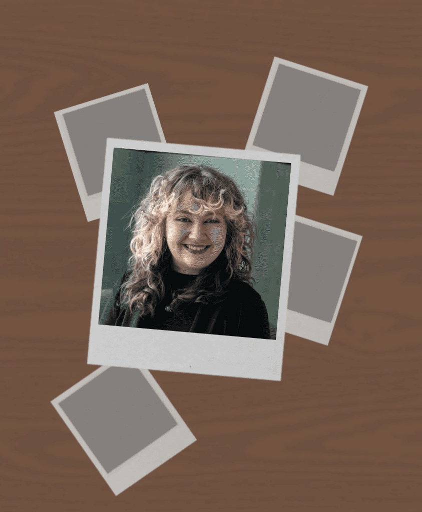 A stack of blank papers and four instant poloriods, one showing a woman with curly hair smiling, on a wooden surface.