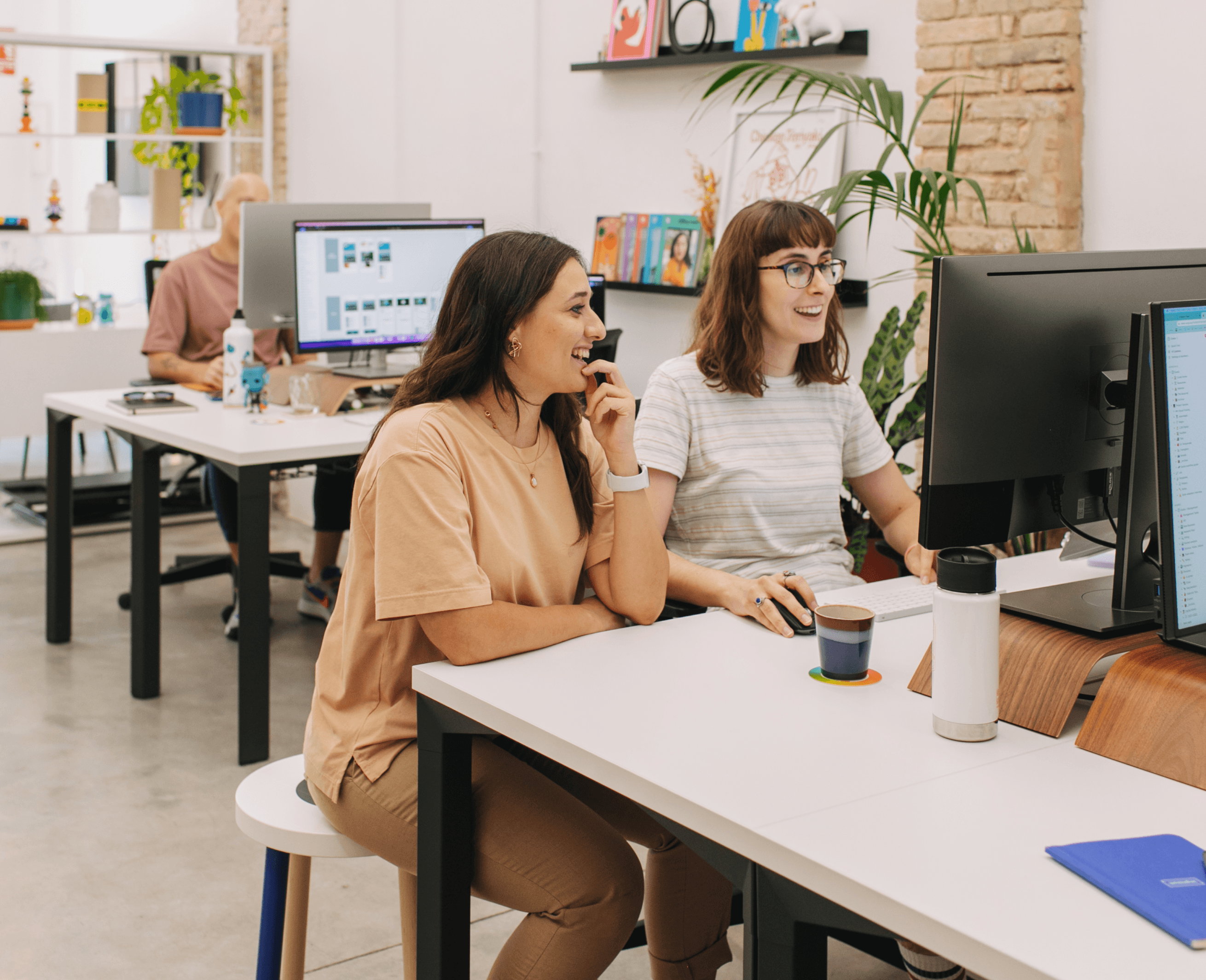 Two designers sitting at a desk, looking at work.