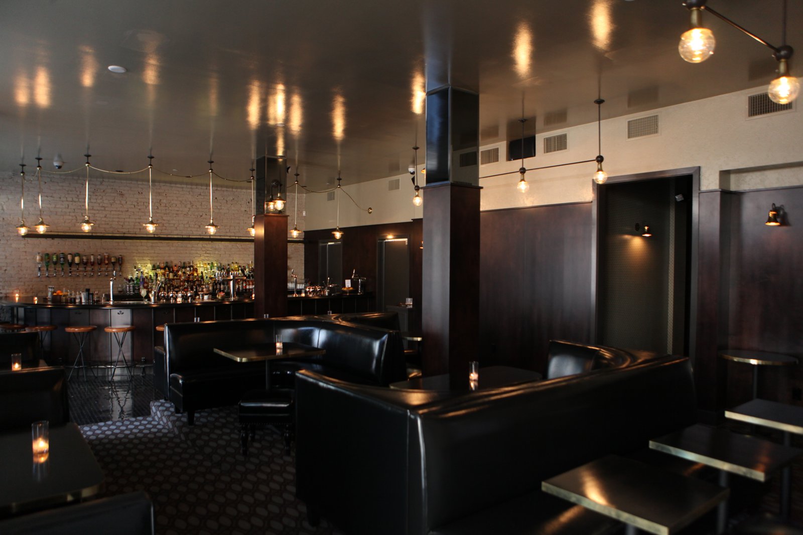 Leather booths and curved bar beneath a reflective ceiling.