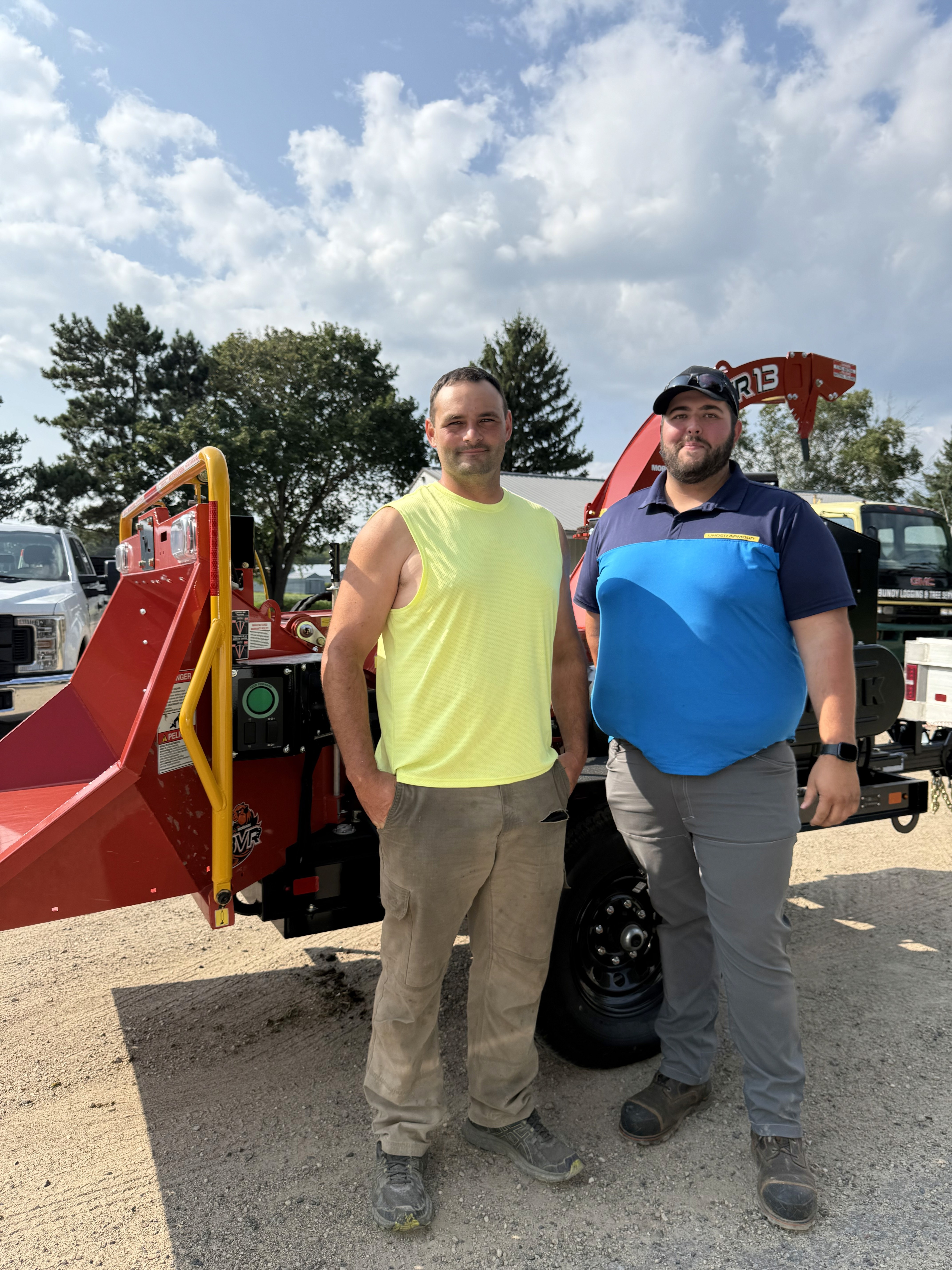 Joe, owner and operator of Bundy Logging and Tree Service, stands with a Morbark representative beside the company's new Morbark wood chipper for tree removal and tree service in Eau Claire, Wisconsin.