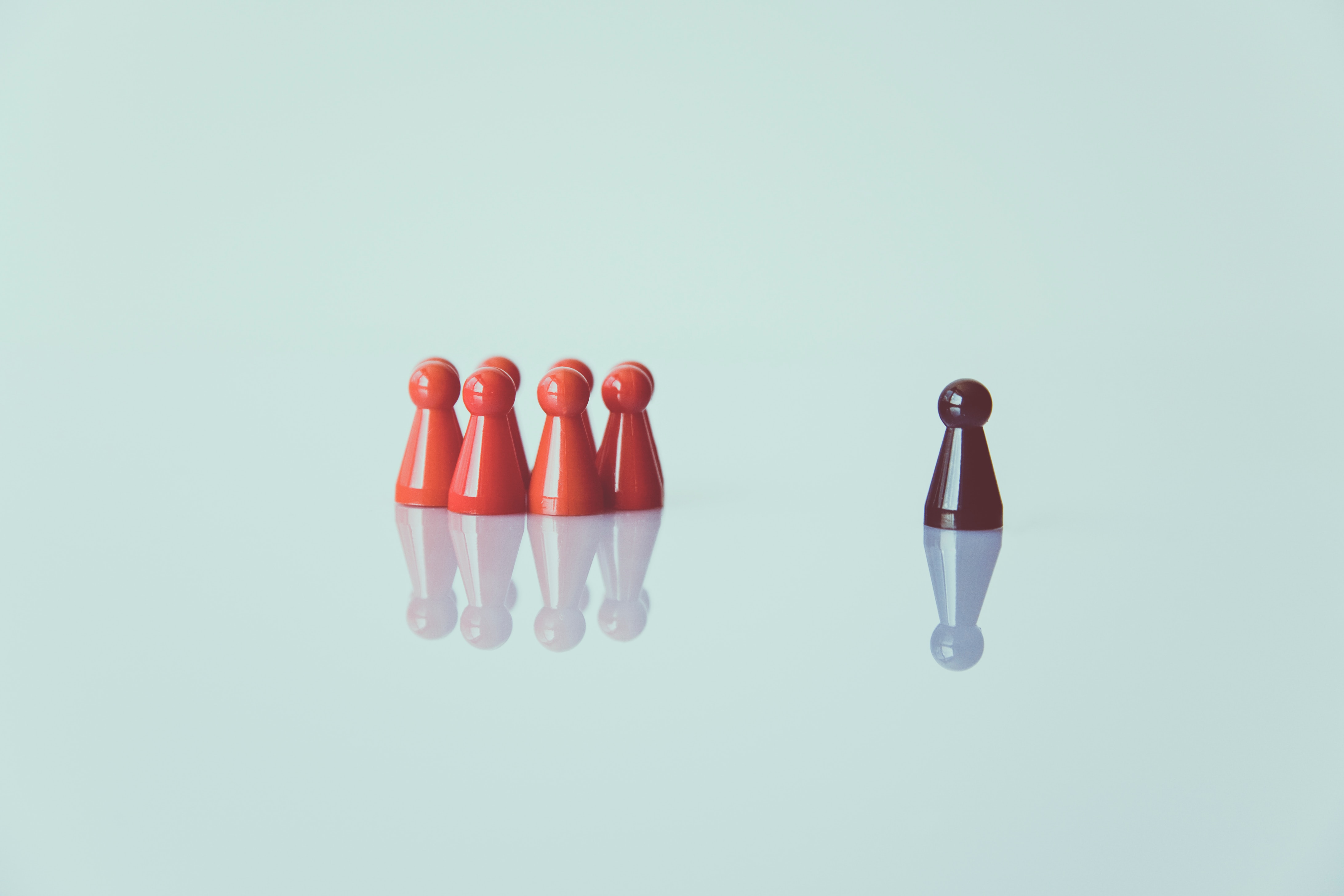 A brown figurine alone and a group of figurines in a group next to the lonely figurine