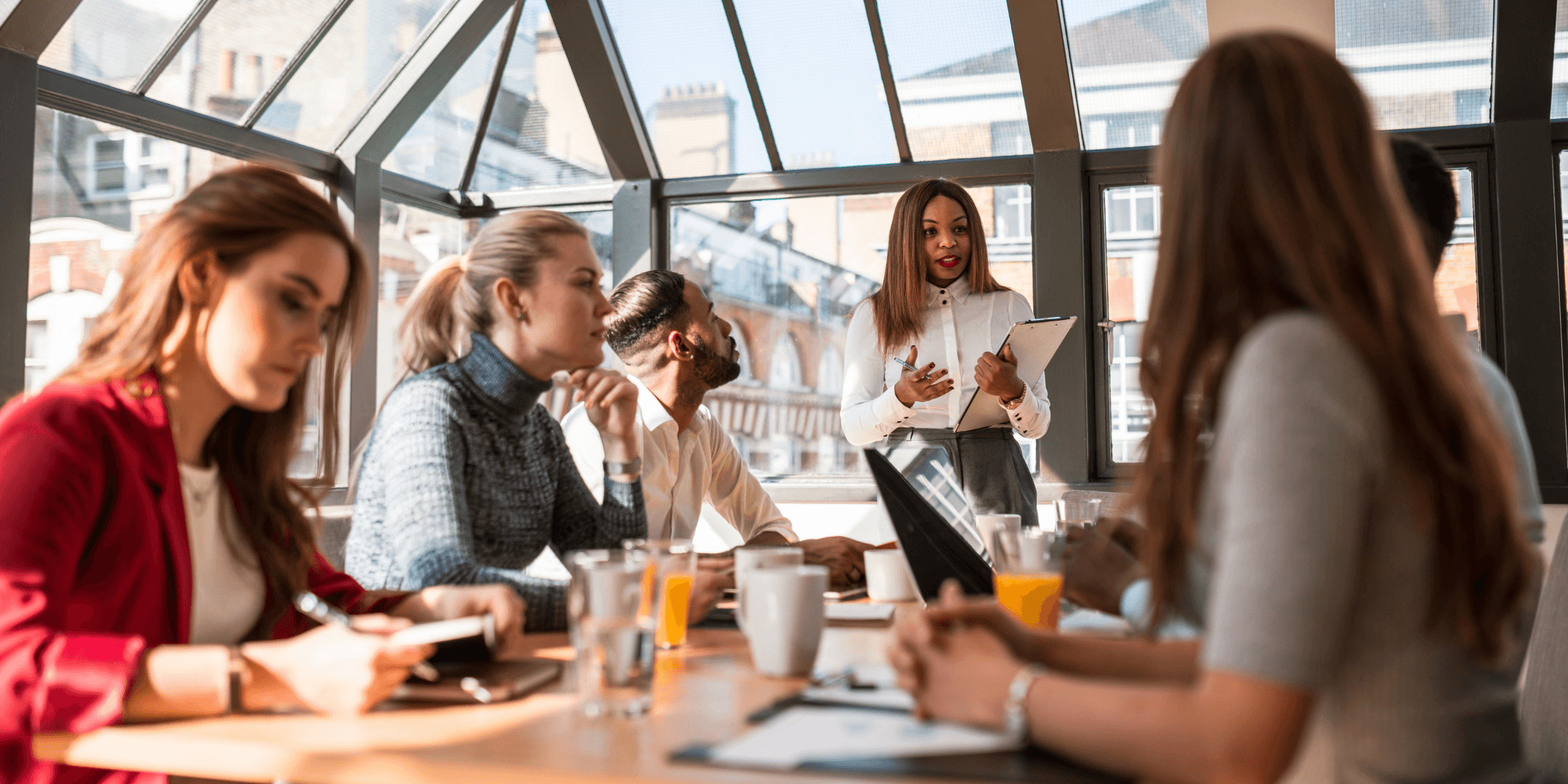 Two people are seated at a table, discussing a document displayed on a laptop screen.